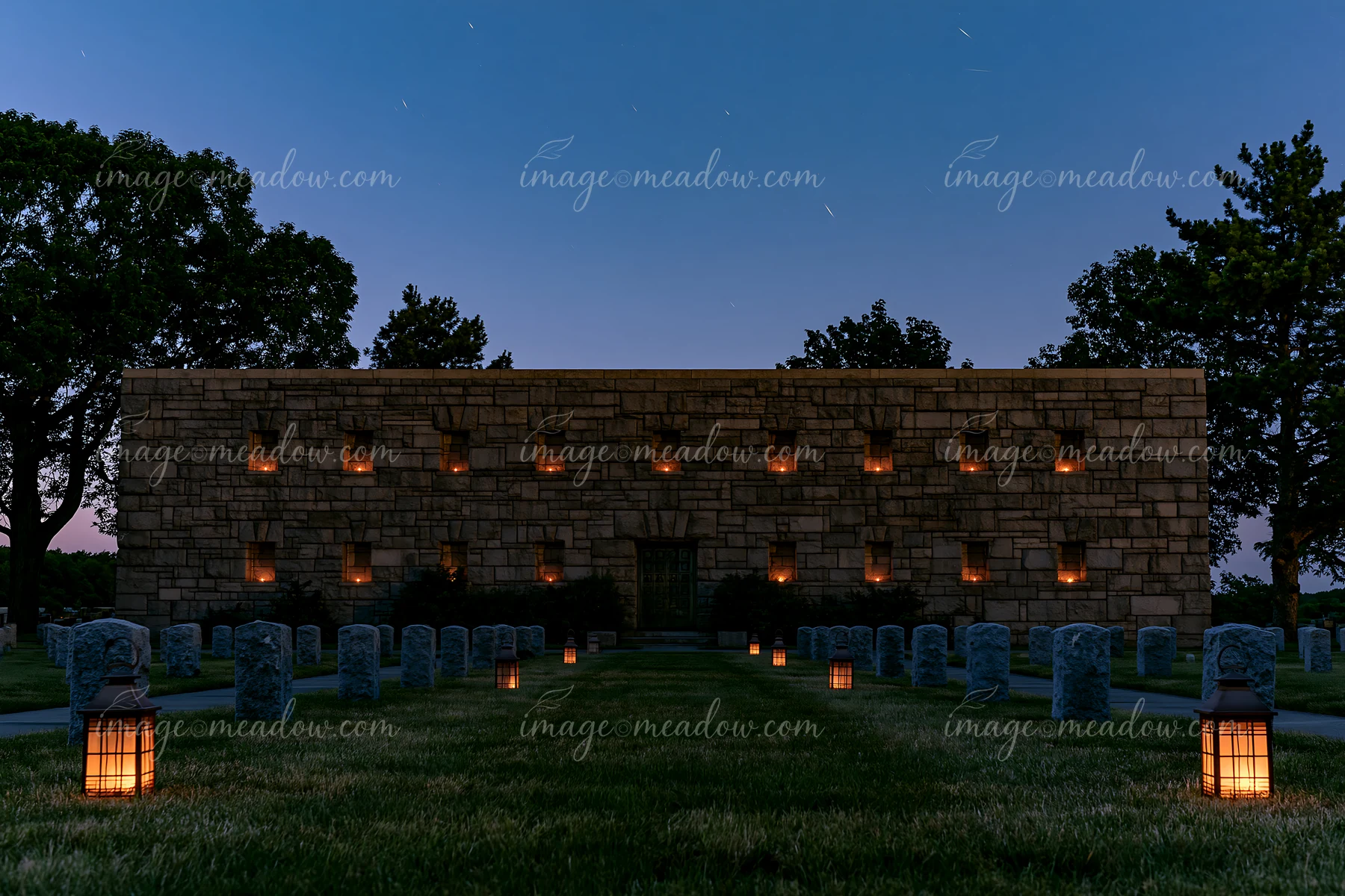 A soldiers' cemetery is illuminated by lanterns, showing headstones aligned in rows.