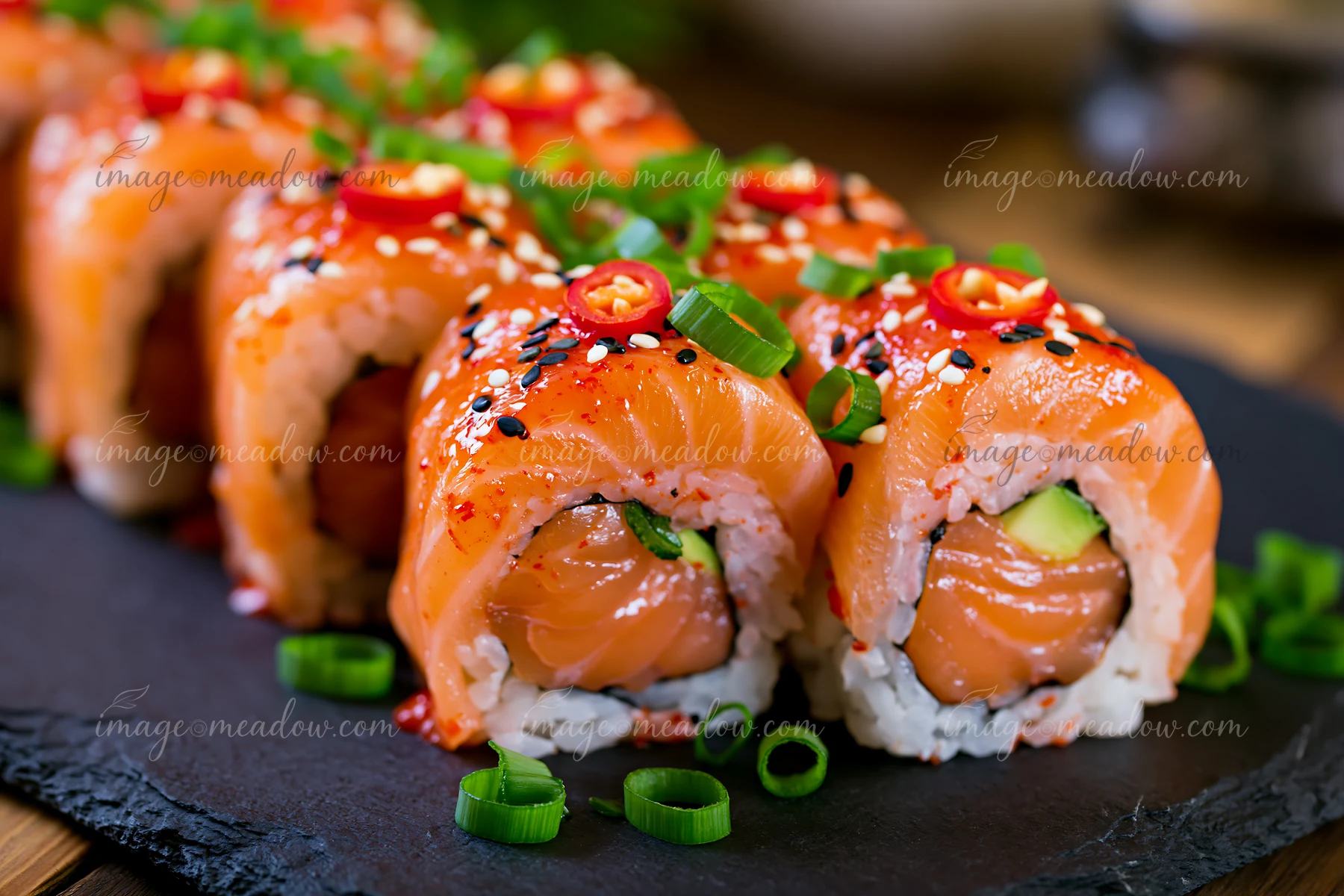 A spicy salmon sushi roll with chili is arranged neatly on a dark plate.
