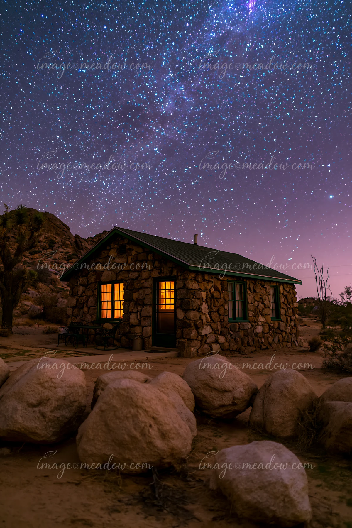 A stone house stands in a desert with a starry sky overhead.
