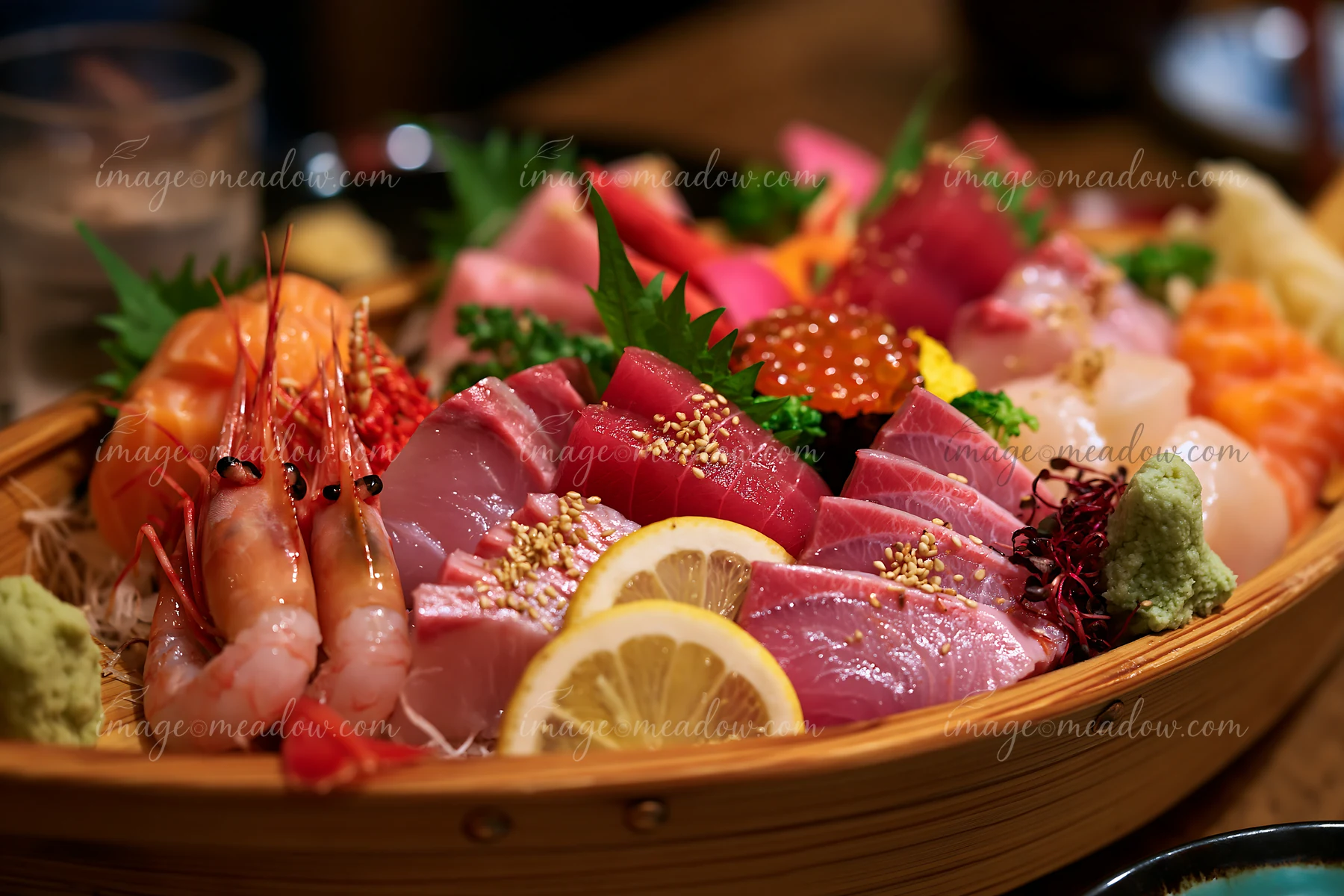 A sushi boat with assorted seafood features various types of fish, shrimp, and garnishes presented on a wooden platter.