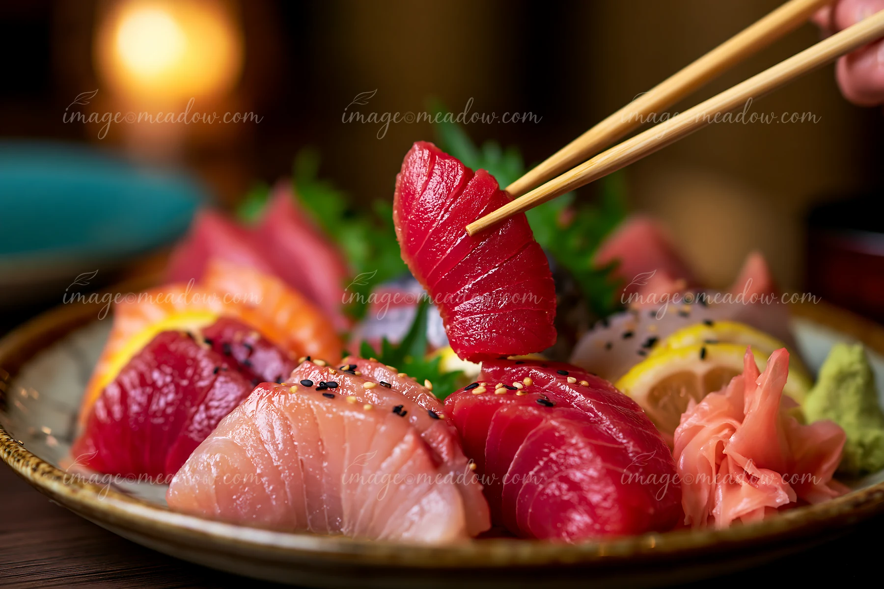 A sushi lover picks up a slice of fresh sashimi from a vibrant platter featuring various types of fish, garnished with pickled ginger and wasabi in a restaurant