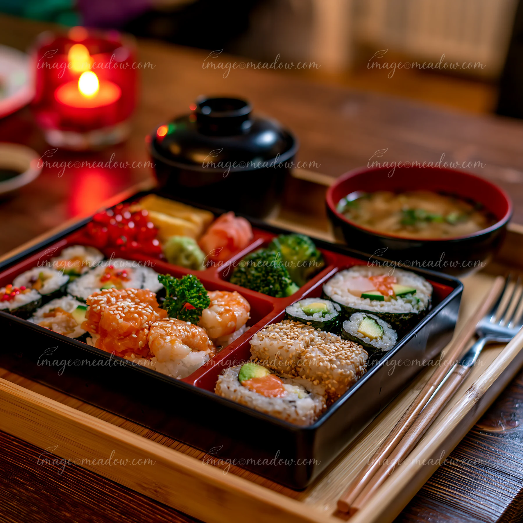 A sushi lunch box with compartments holds various sushi types, sides, and soup.