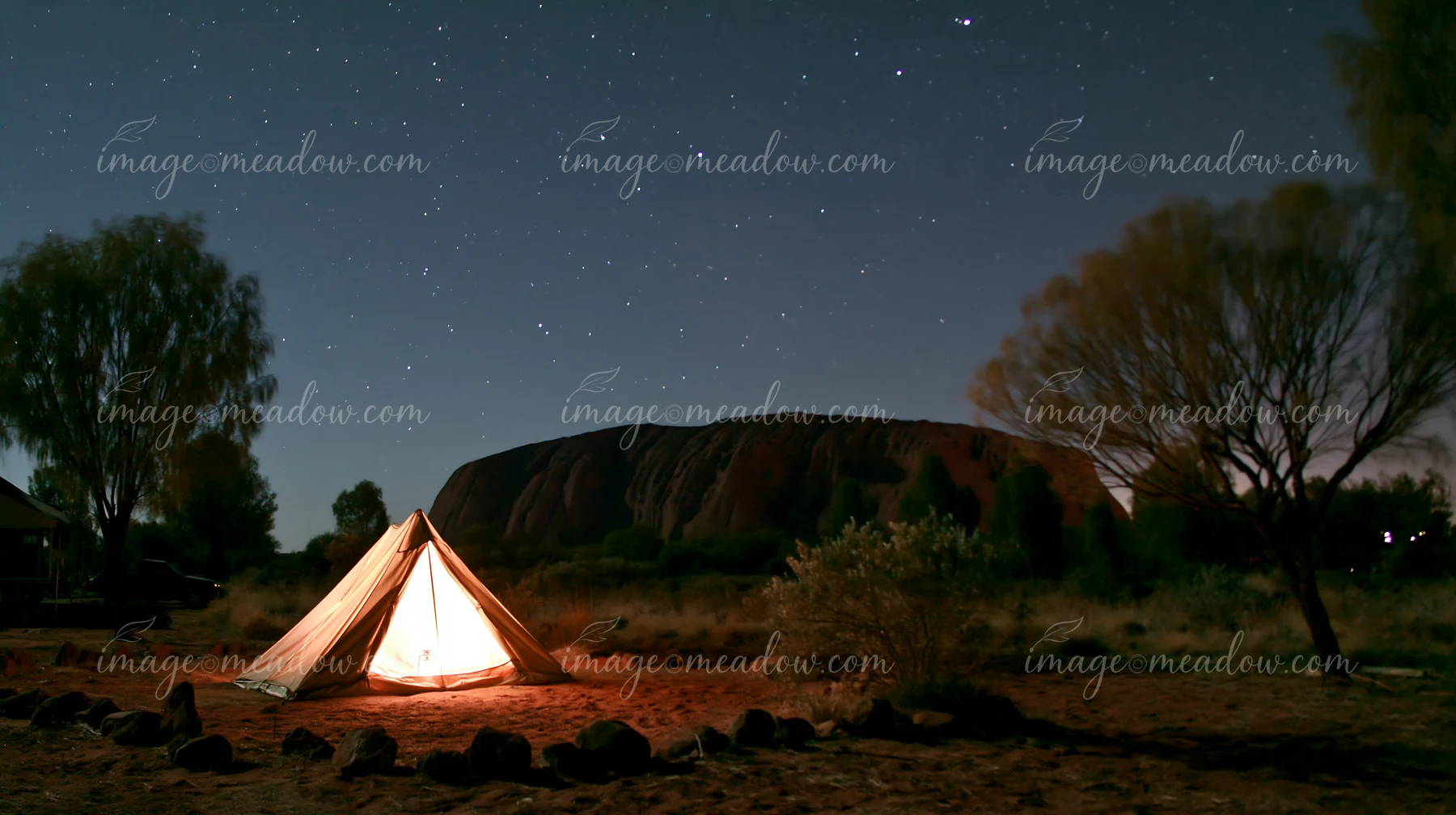 A tent sits in the foreground with Uluru rising majestically behind it.