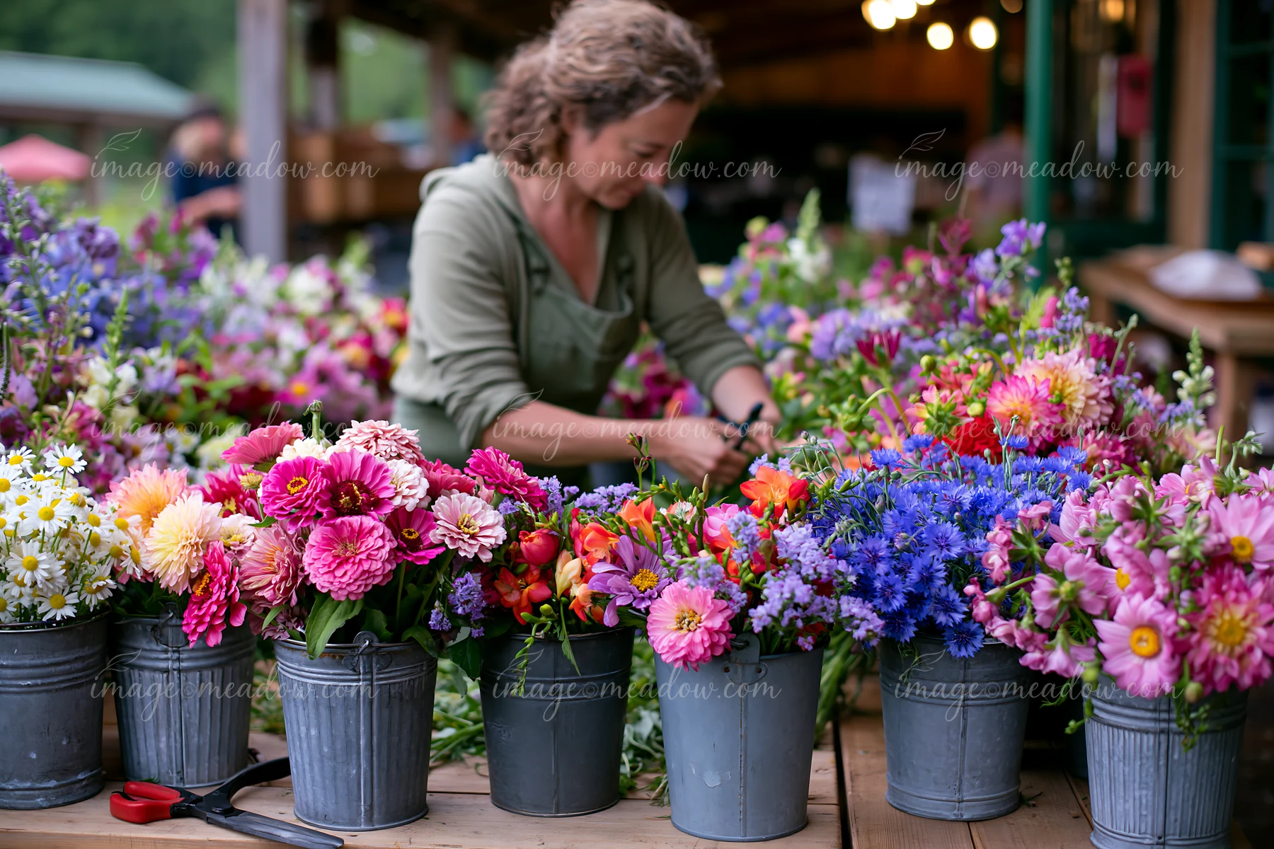 A vendor arranges mixed seasonal flowers at a farmers market.