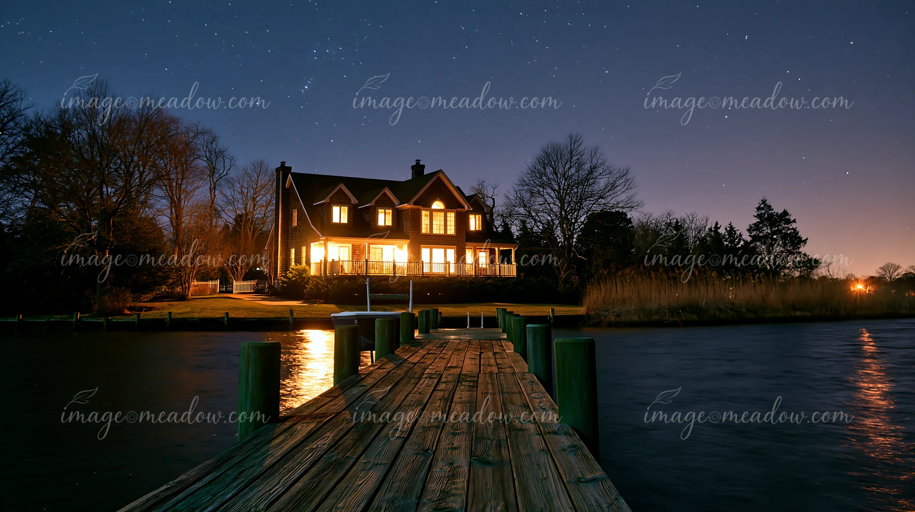 A villa stands by the water under a sky filled with stars.