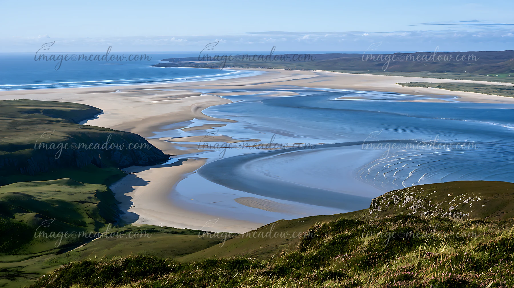 A wide sandy beach bordered by water, set against rolling hills under a clear blue sky.
