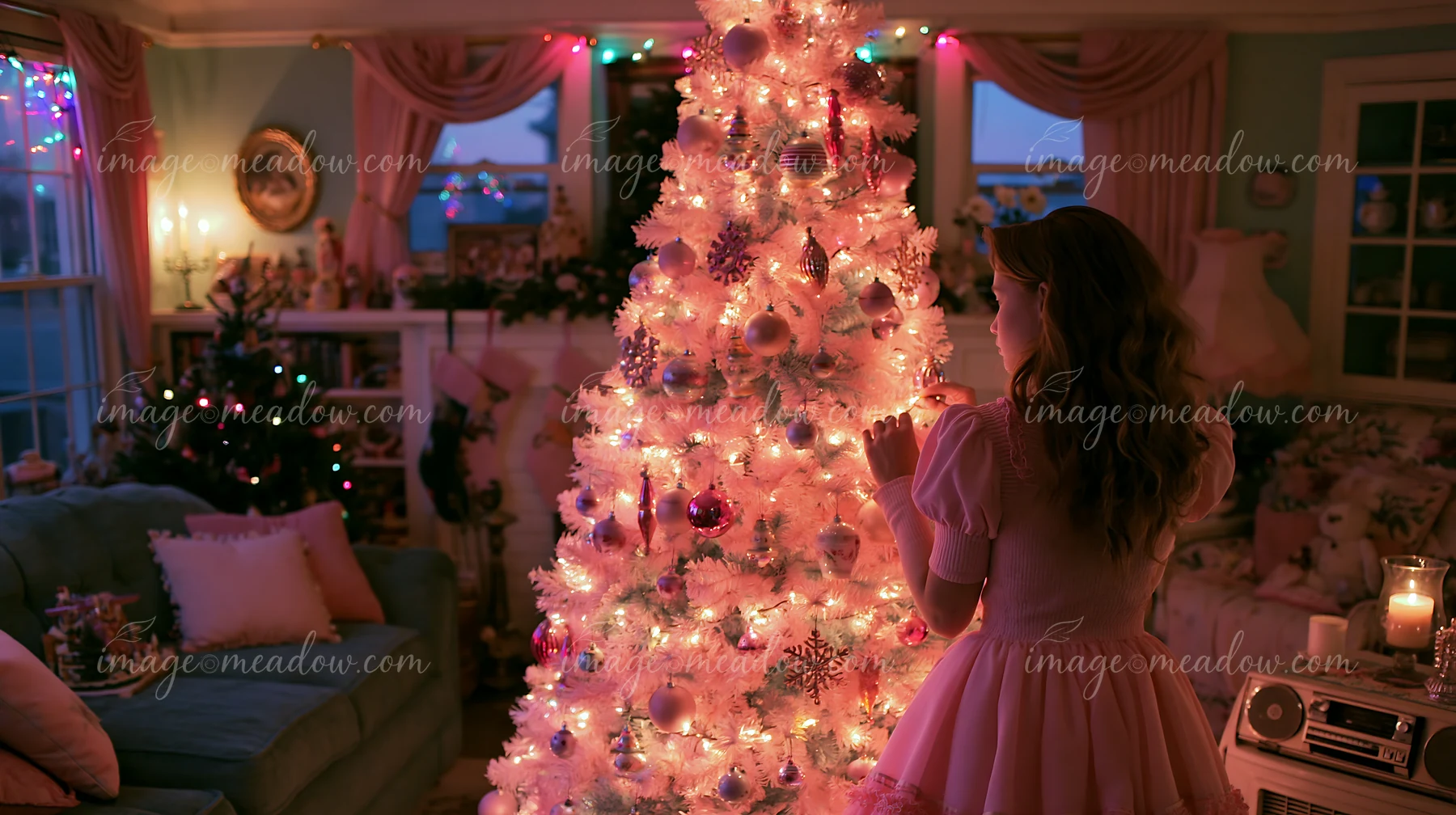 A woman decorates a Christmas tree in a living room filled with pastel decorations and warm lights.