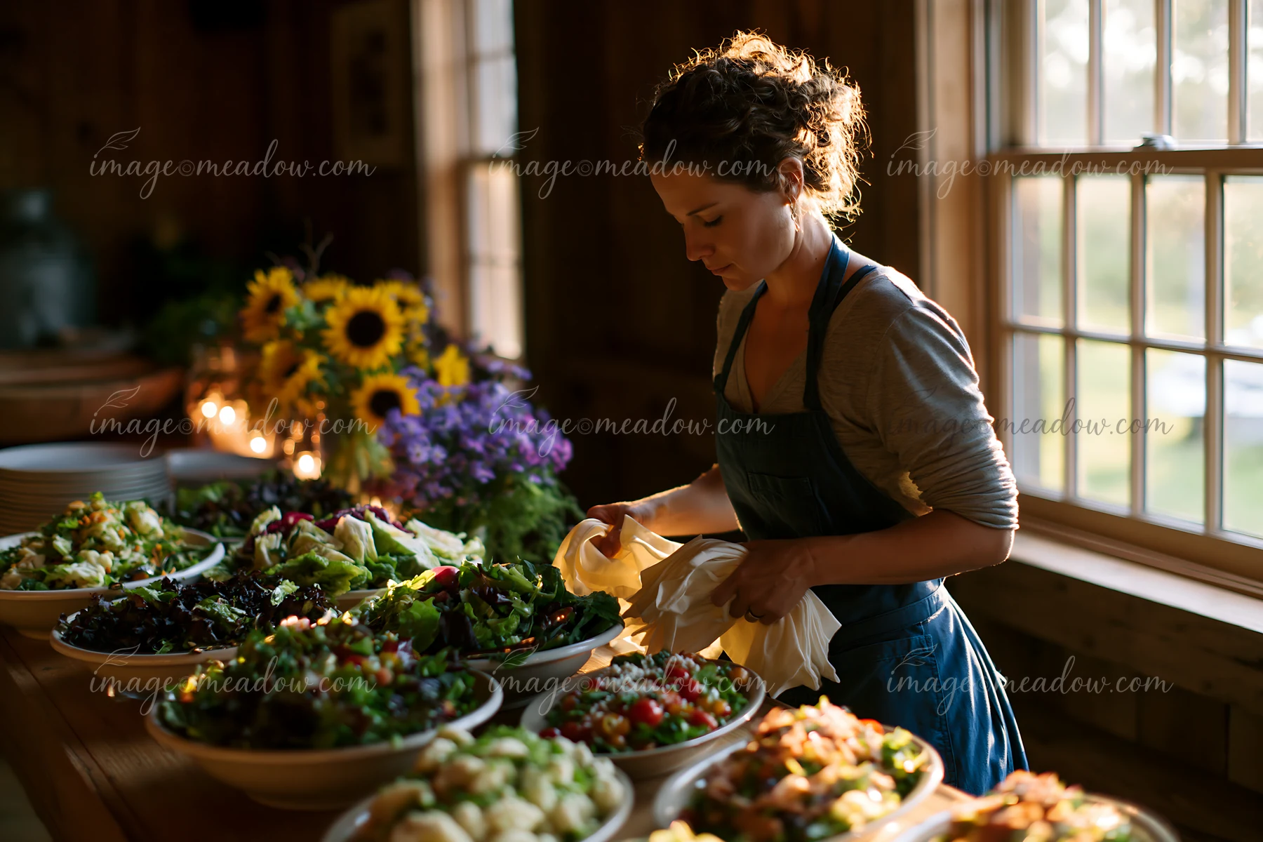 A woman prepares a variety of salads in a rustic wooden space filled with natural light.