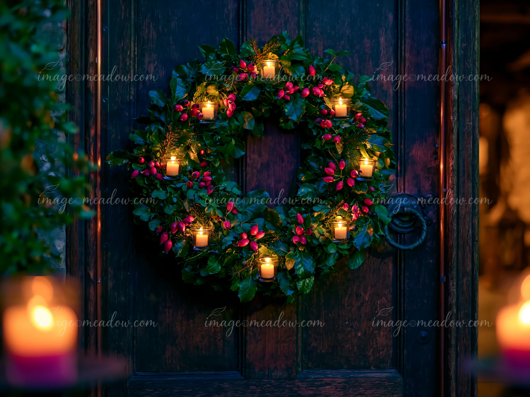 A wreath made of greenery and red berries decorates a wooden door.