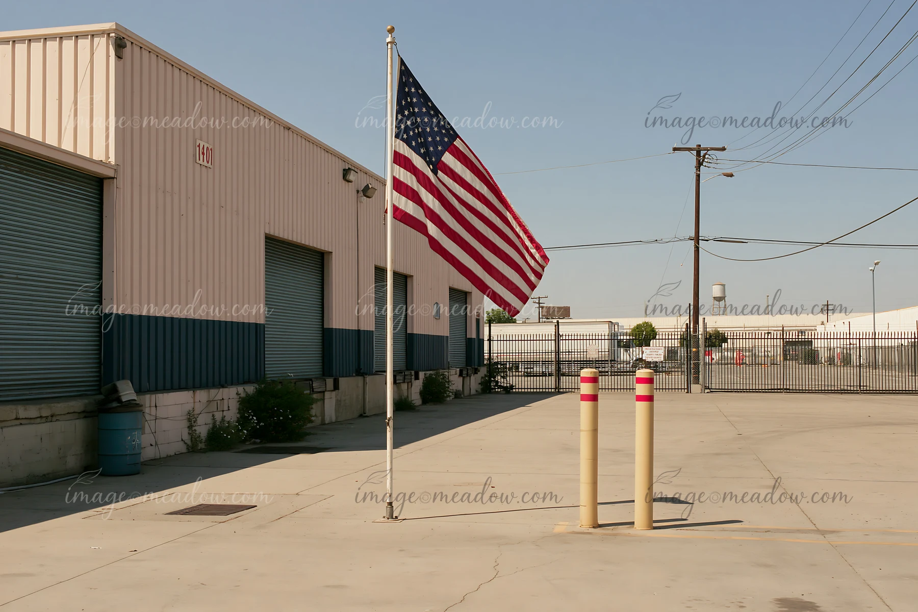 An American flag waves proudly outside a factory in an industrial area during daylight.