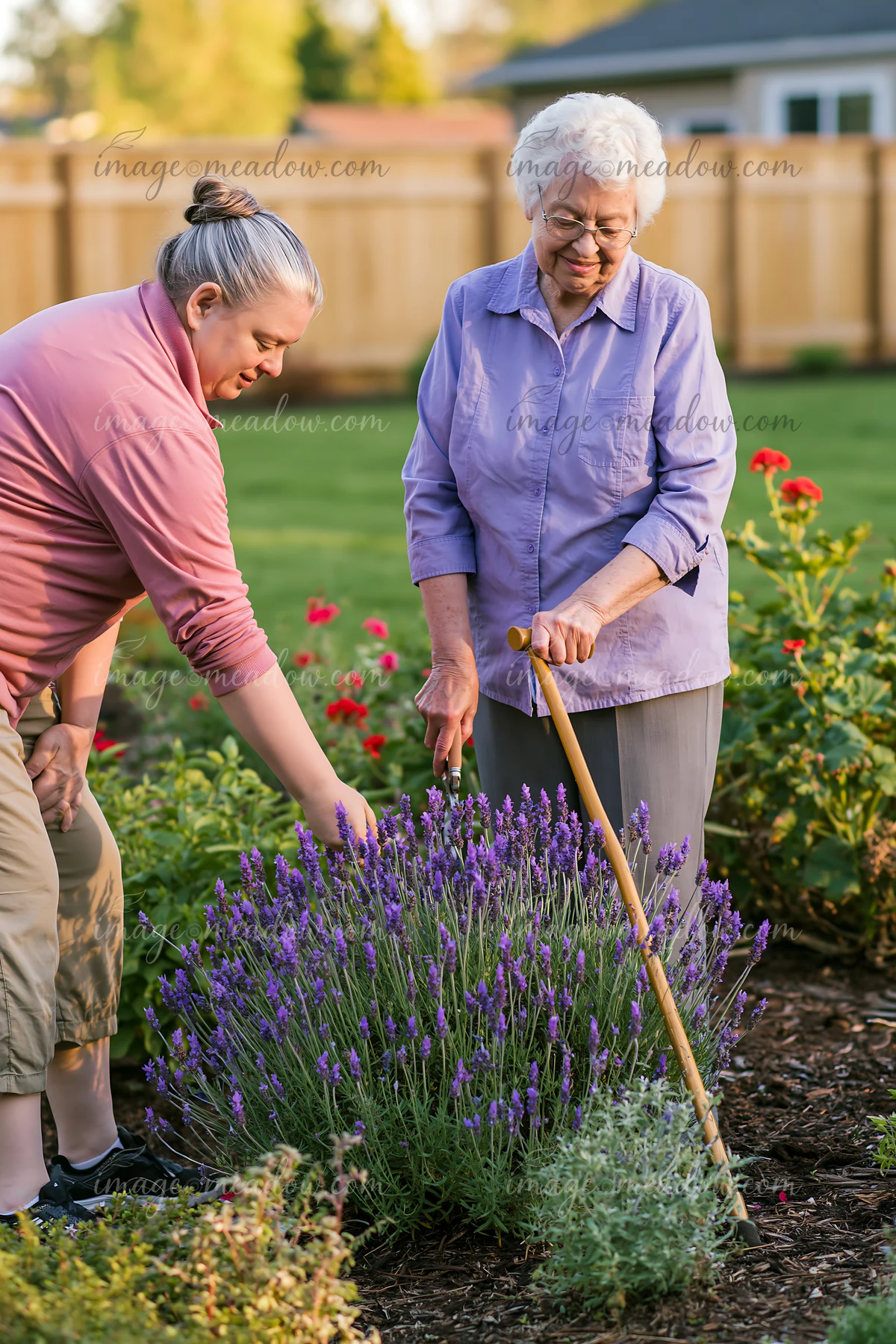 An elderly woman with Alzheimer's is gardening in a backyard with the support of a caregiver.