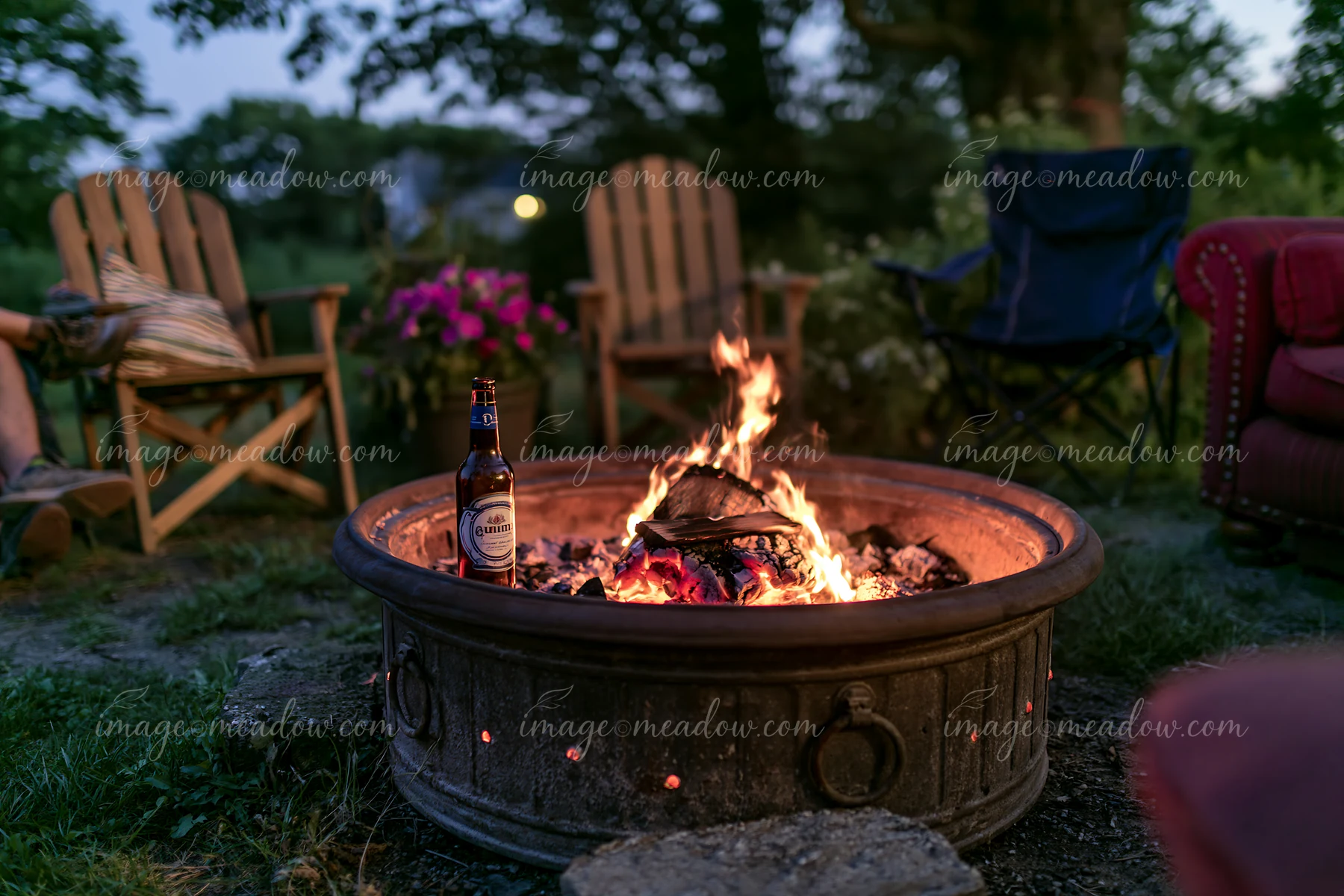 An empty bottle after party sits beside a fire pit surrounded by chairs.