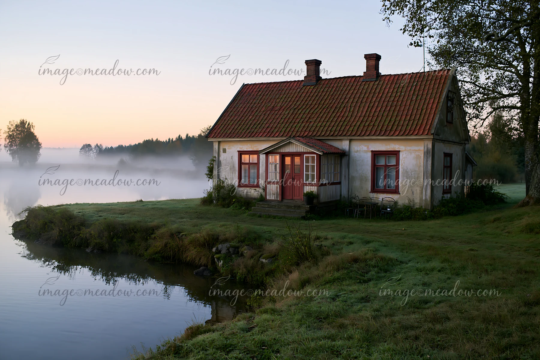 An old cottage with weathered facade stands by a quiet waterway at dawn.