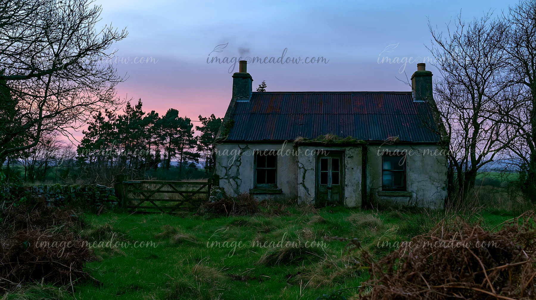 An old cottage with weathered facade stands in a grassy field.