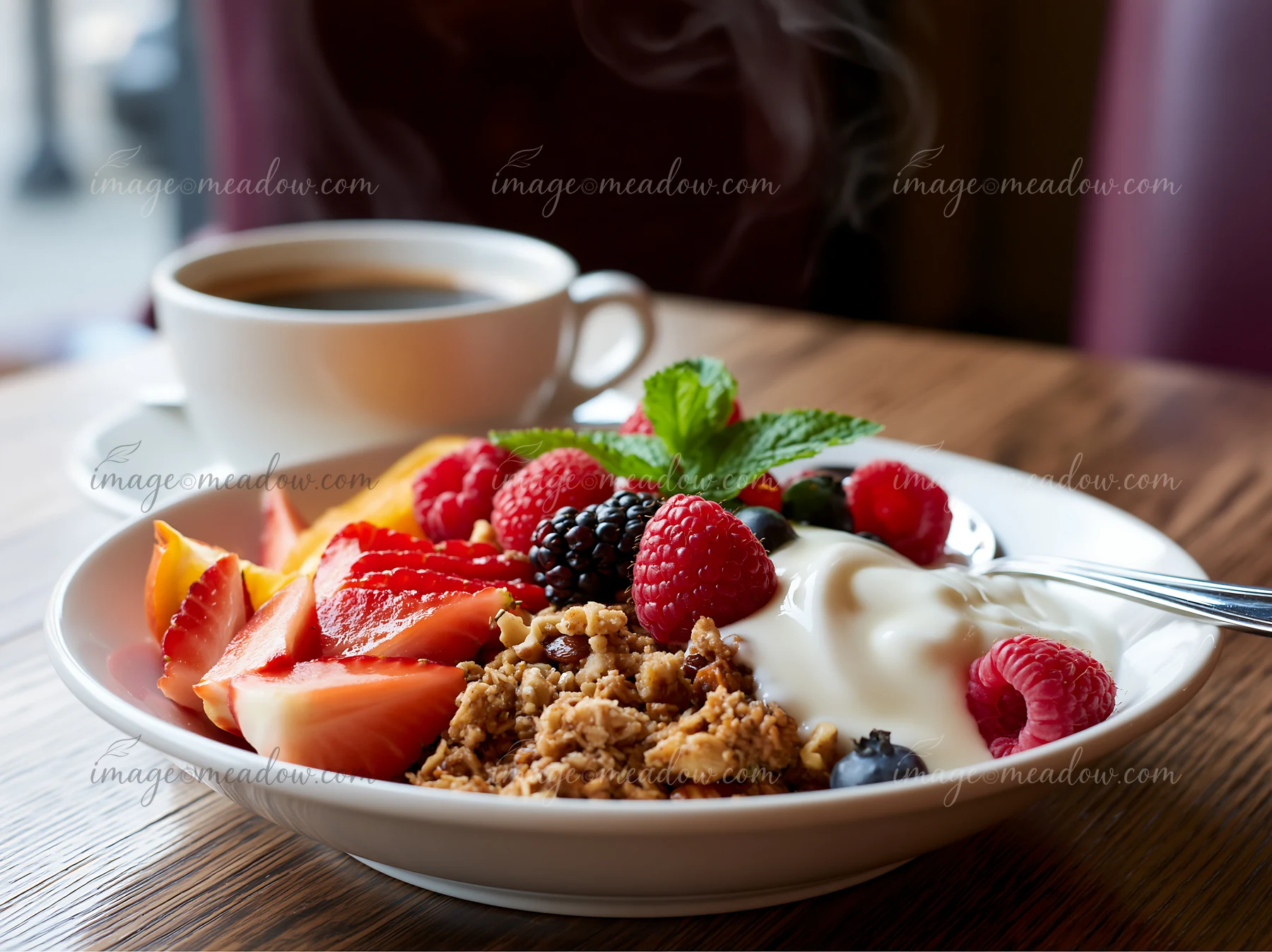 Breakfast plate with muesli includes fresh fruits like strawberries, raspberries, and blackberries alongside yogurt.