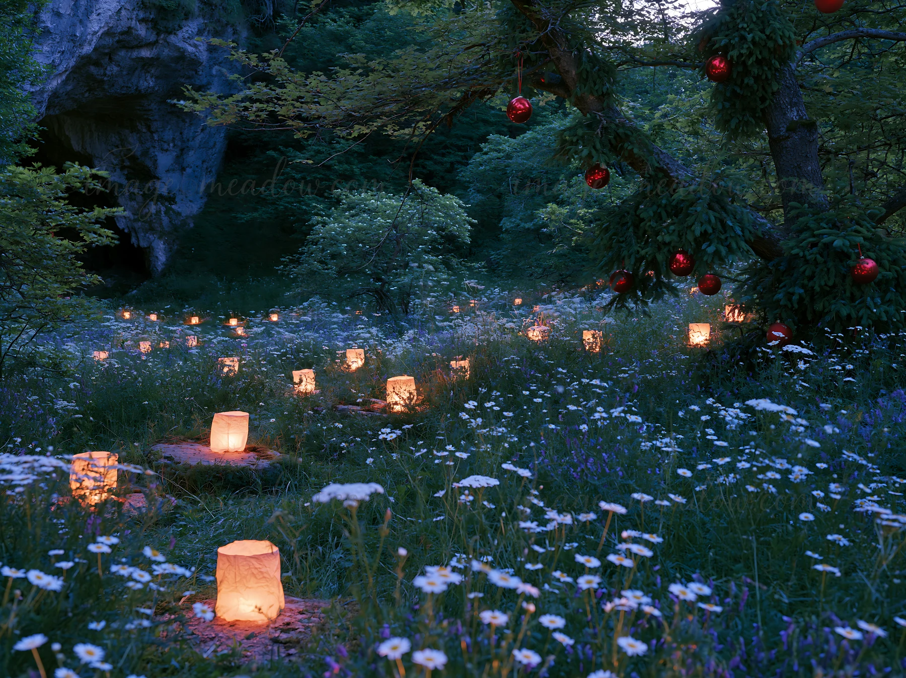 Lanterns light up a meadow filled with wildflowers during dusk, near a cave. The soft glow of the lanterns adds warmth to the natural setting, creating an invit