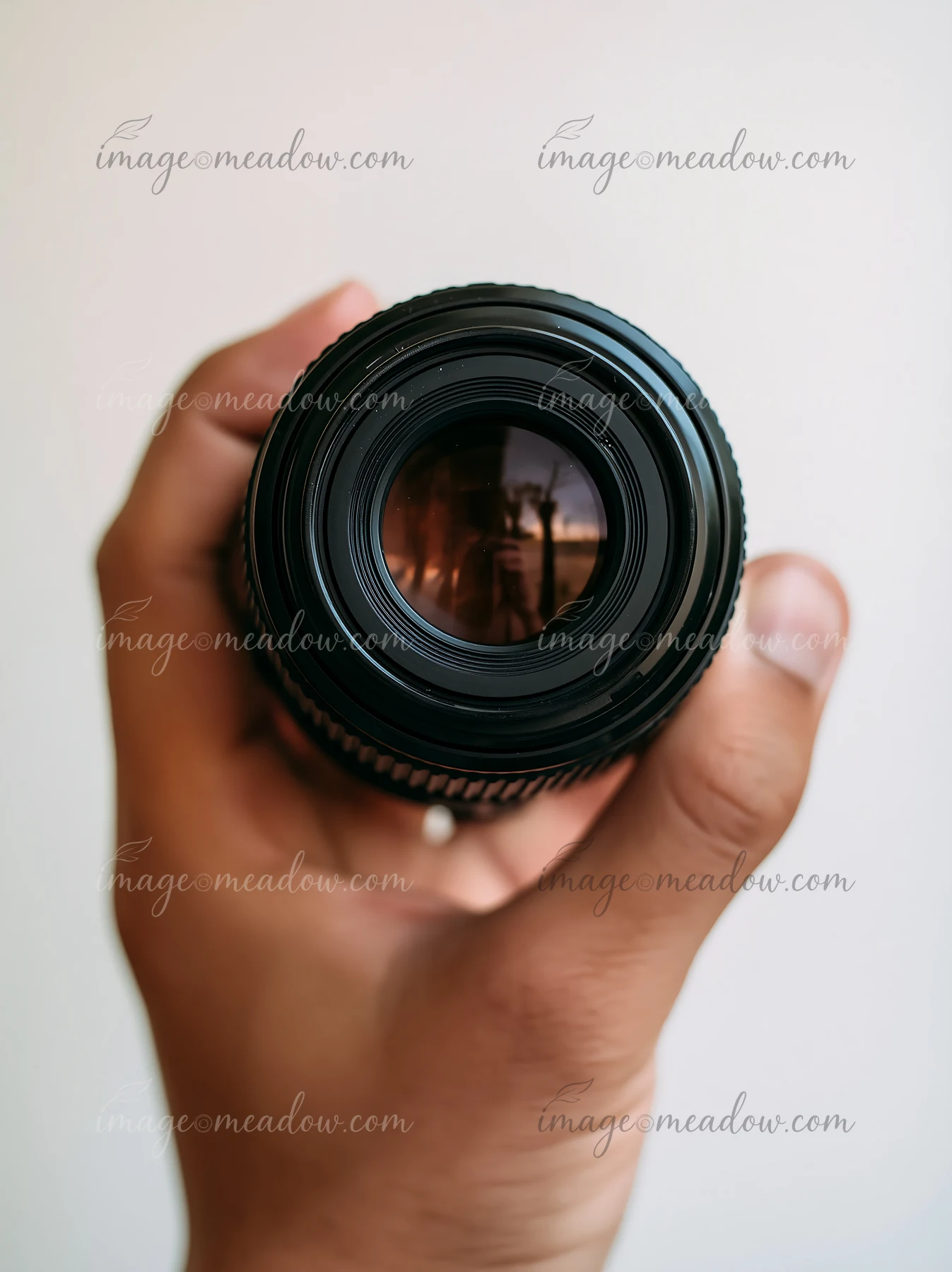 Close-up of camera lens with natural light showing a hand holding the lens.