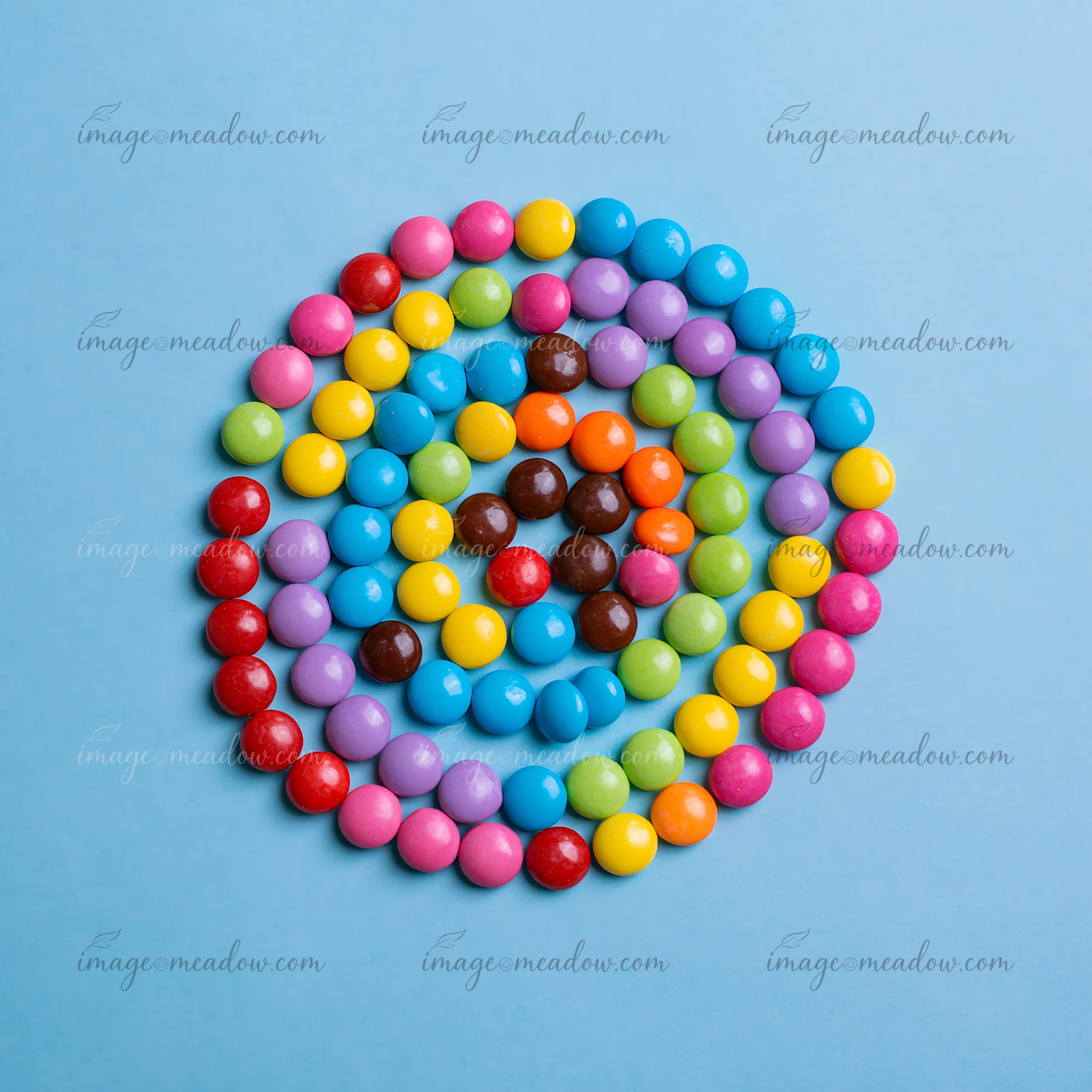 Colorful candy pieces forming spiral create a vibrant design against a blue background.