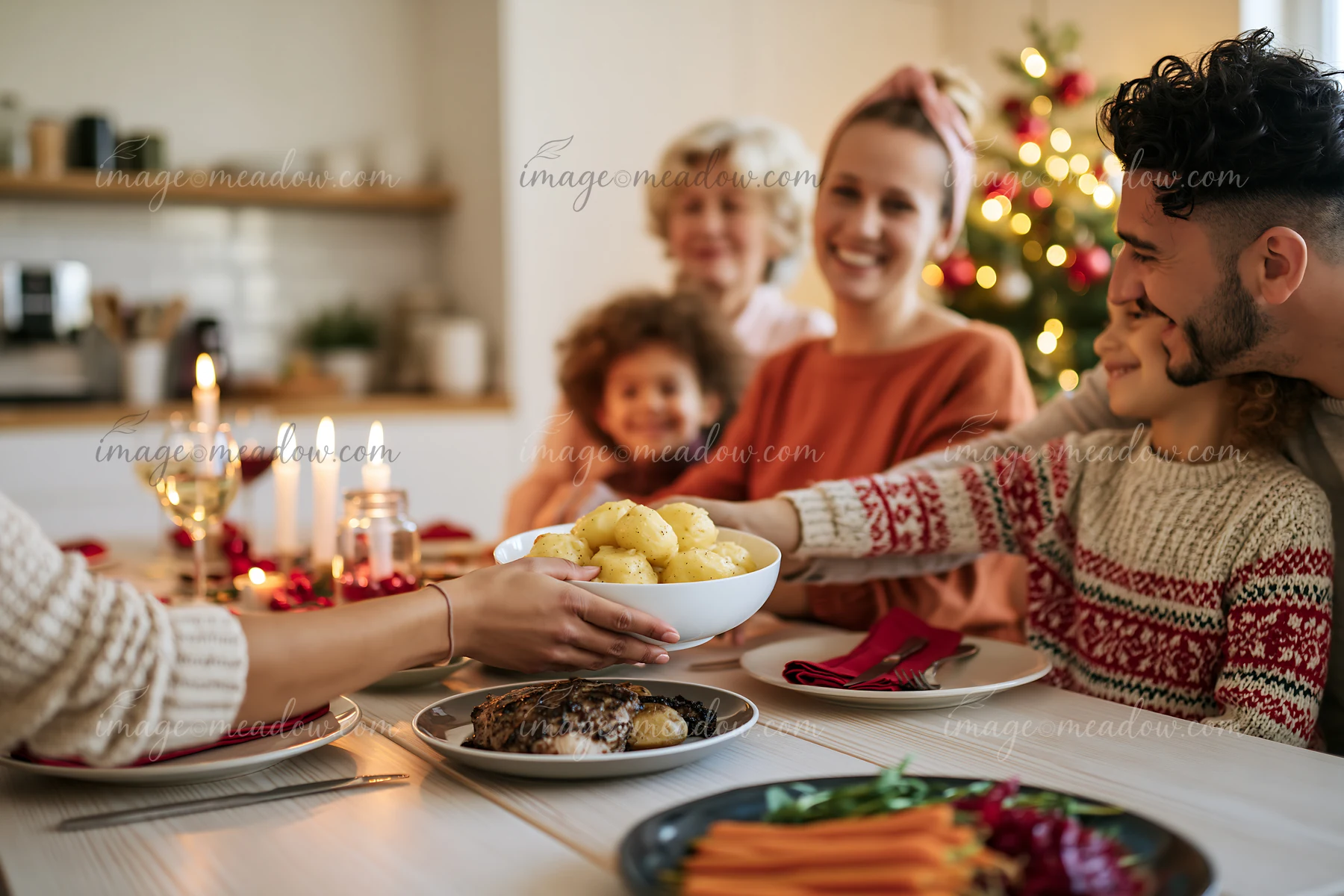 Family members share a Christmas meal around a dining table while passing a bowl of potatoes.