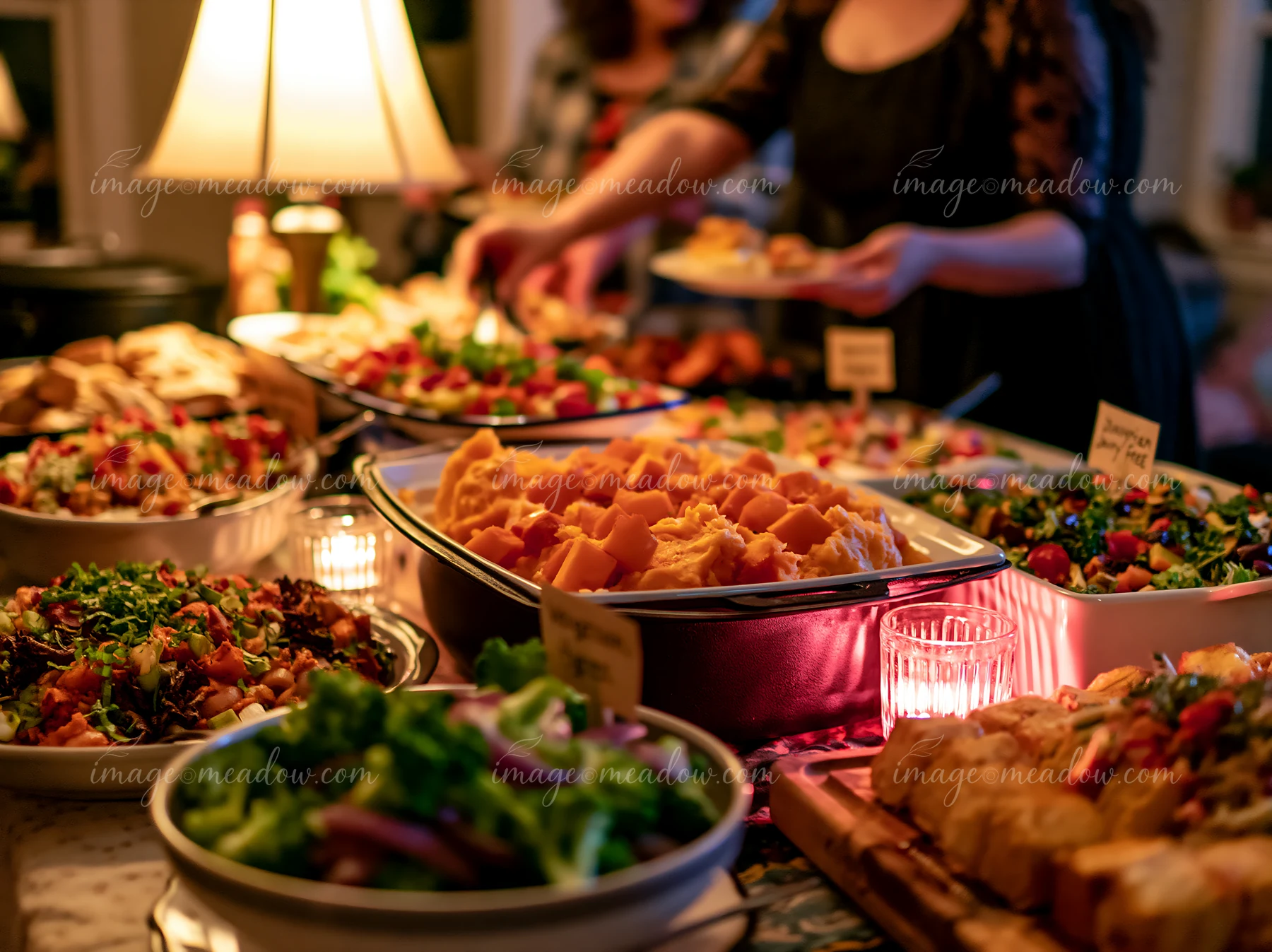 Guests serve themselves from a warmly lit buffet with food dishes and dietary labels.