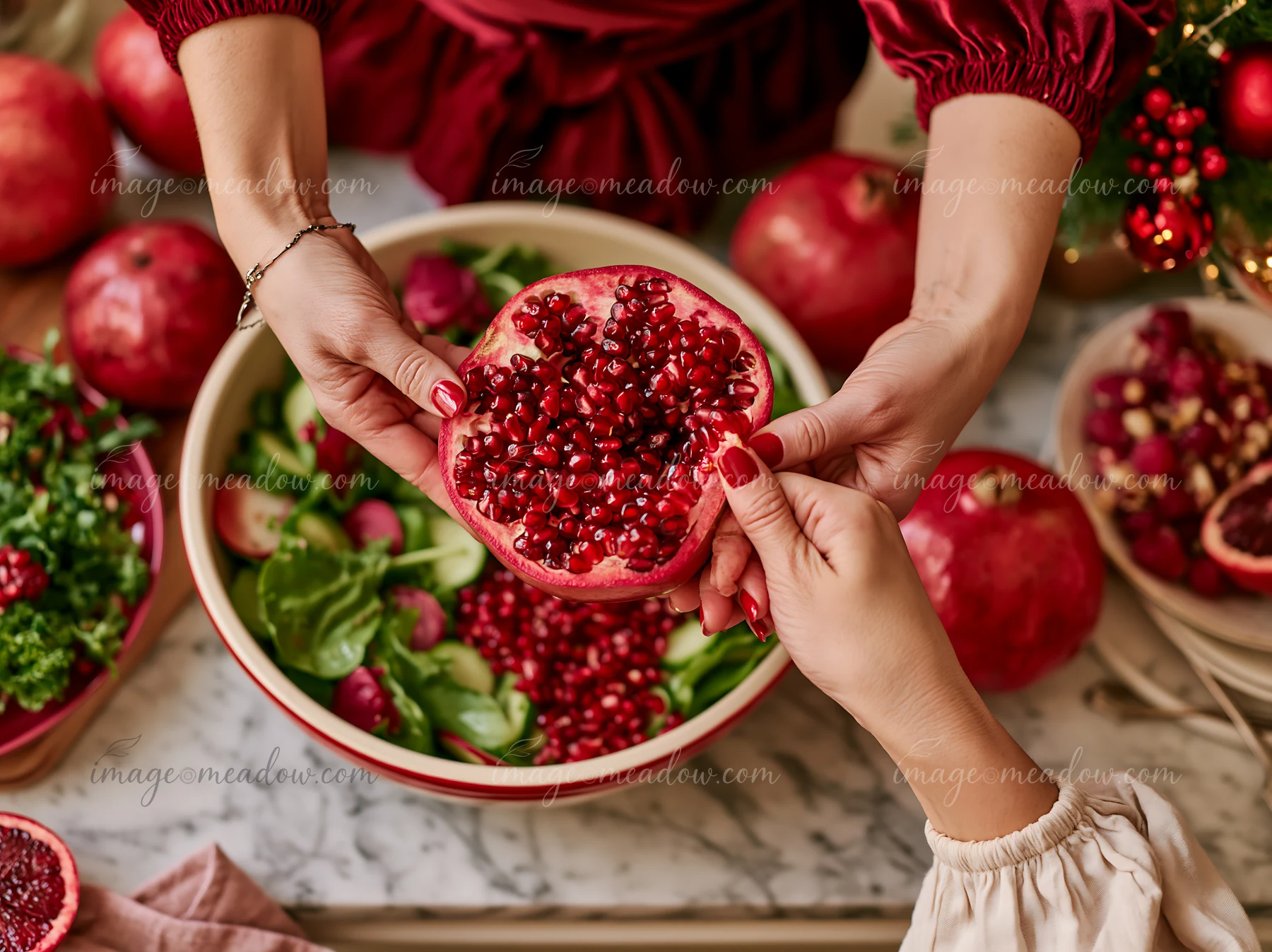Hands prepare pomegranate seeds for a Christmas dinner in a kitchen filled with festive decorations.
