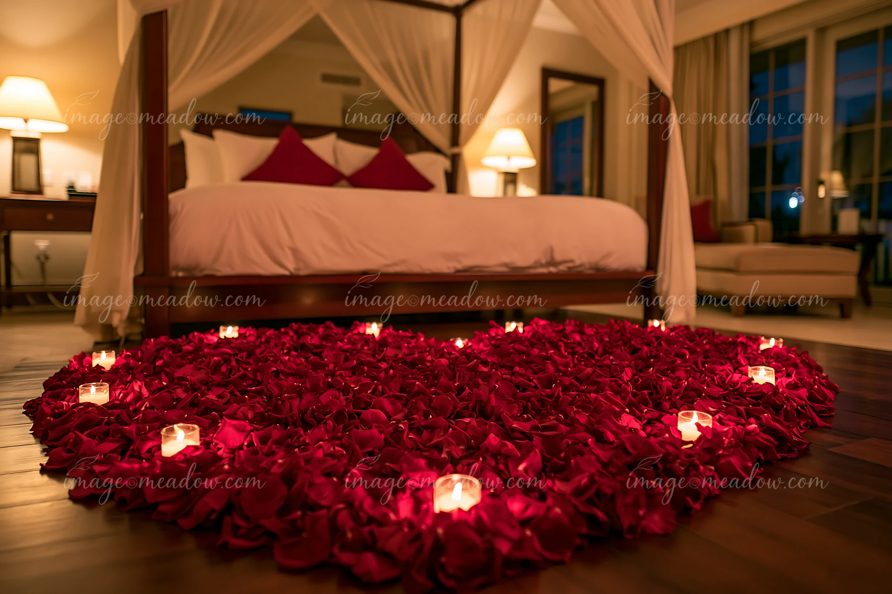 Heart-shaped flower petals arranged on bed with candles in a romantic setting.