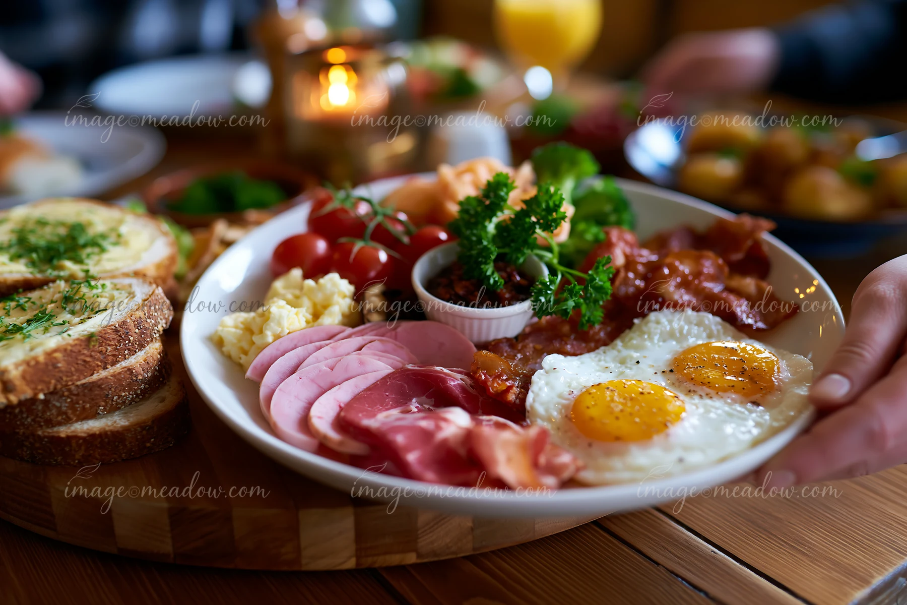 Hearty breakfast platter with fried eggs, bacon, ham, toast, tomatoes, and greens on a wooden table.