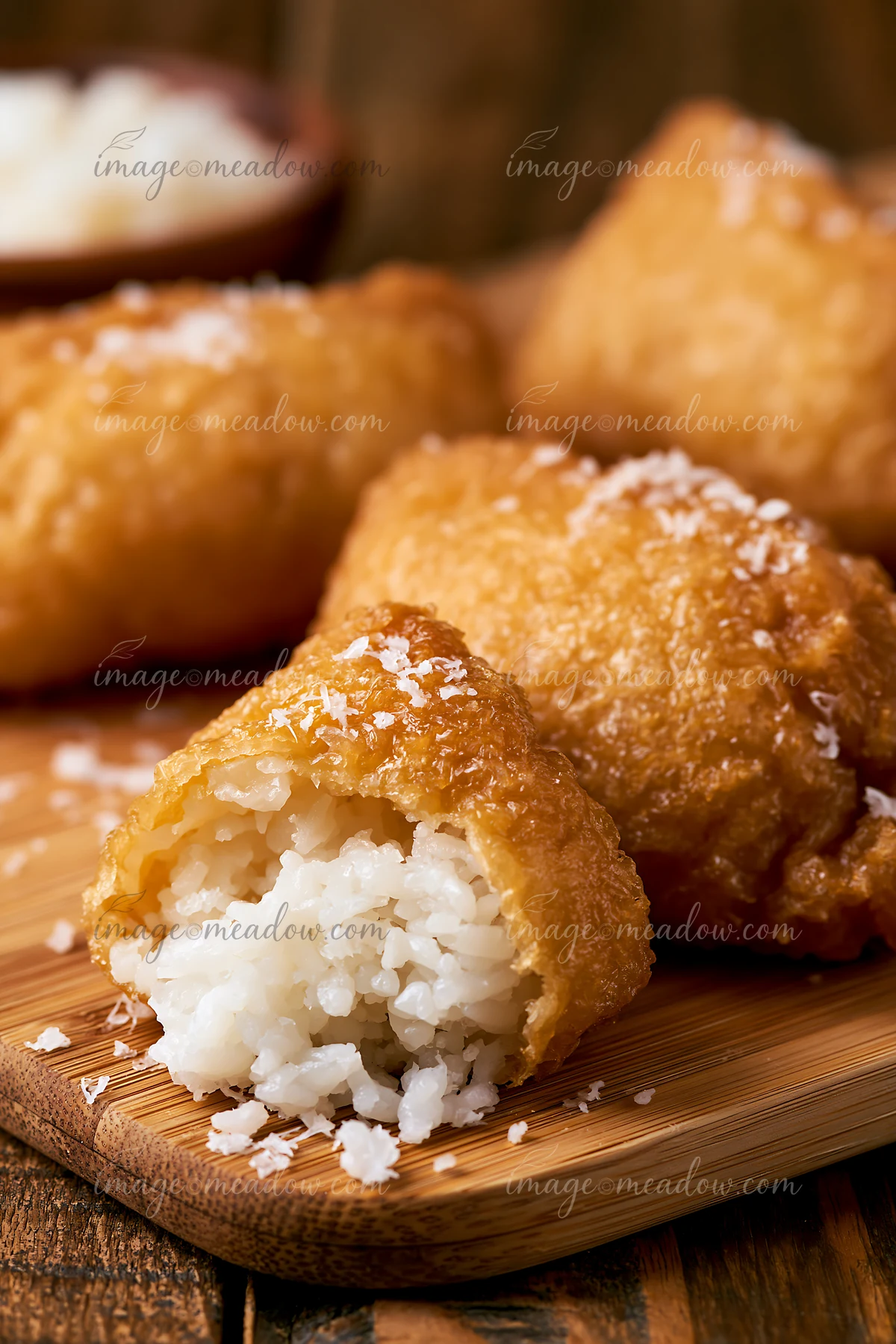 Inari sushi pockets filled with rice are arranged on a wooden board.