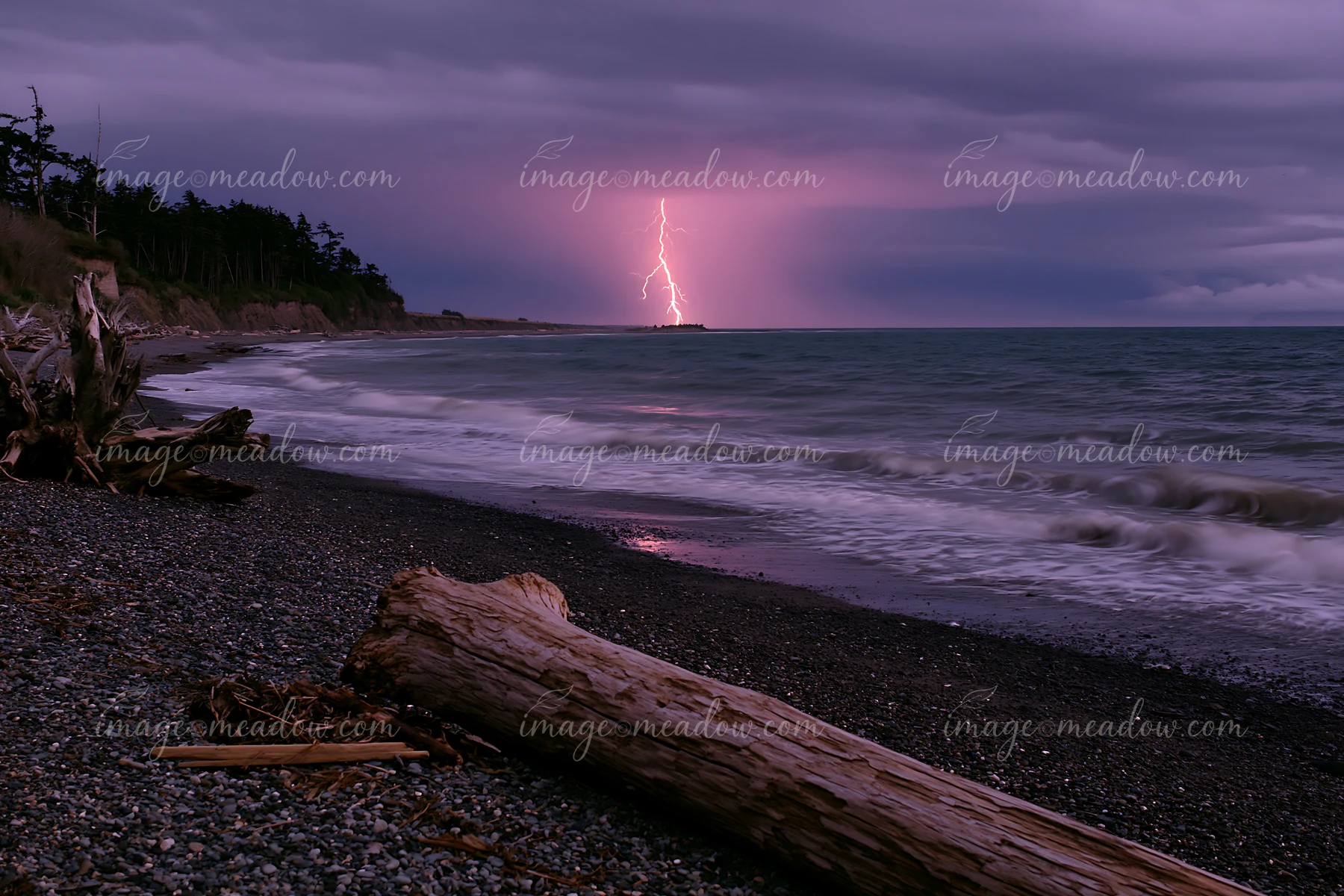 Lightning strikes the ocean near the coastline, illuminating the dark sky.