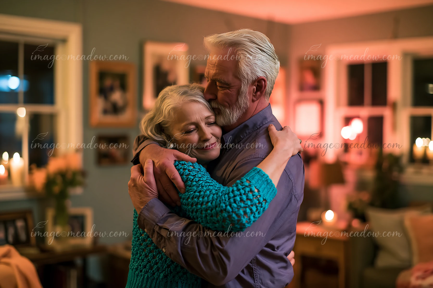Mature couple embraces while dancing in a warmly lit living room.