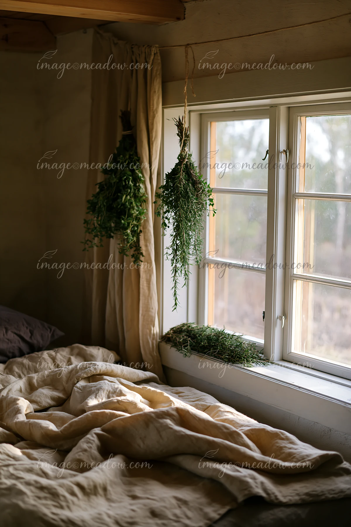Natural light shines through the window onto linen bedding in a rustic bedroom.