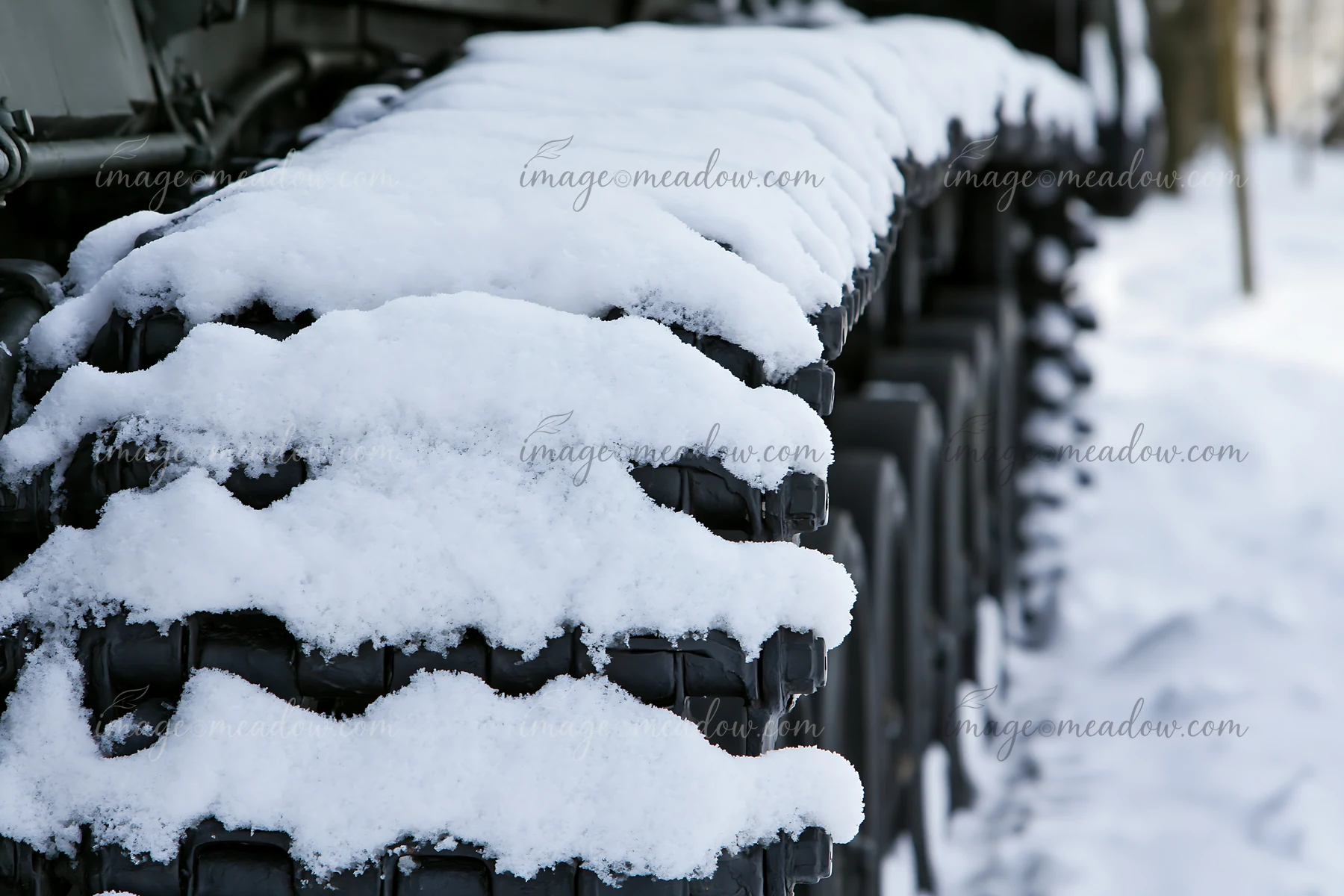 Panzer tank tracks close-up show snow accumulation on chain links in a winter setting.