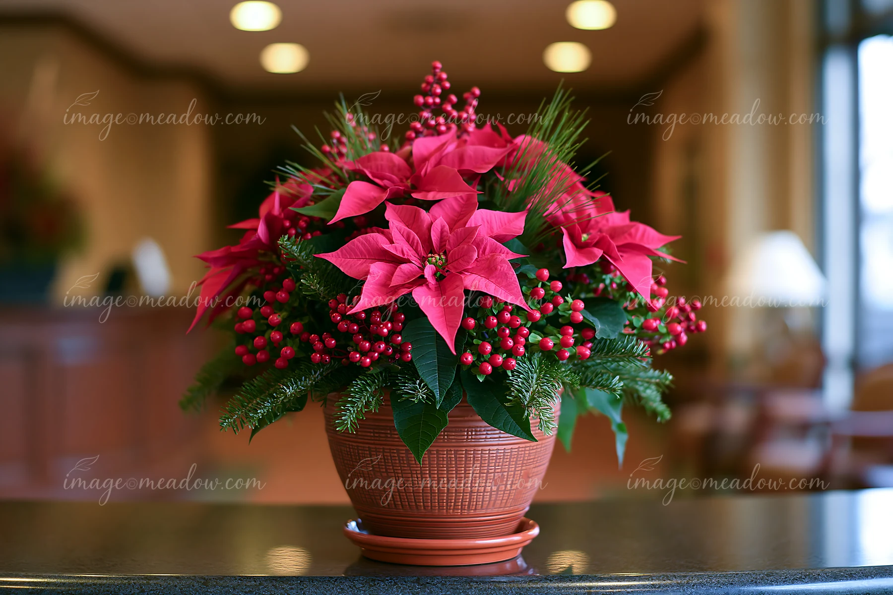 Pink poinsettias, evergreen branches, and red berries form a Christmas arrangement in a ceramic pot indoors.