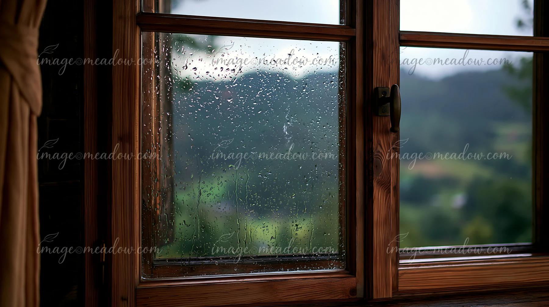 Raindrops on timber window create a clear view of blurred hills.