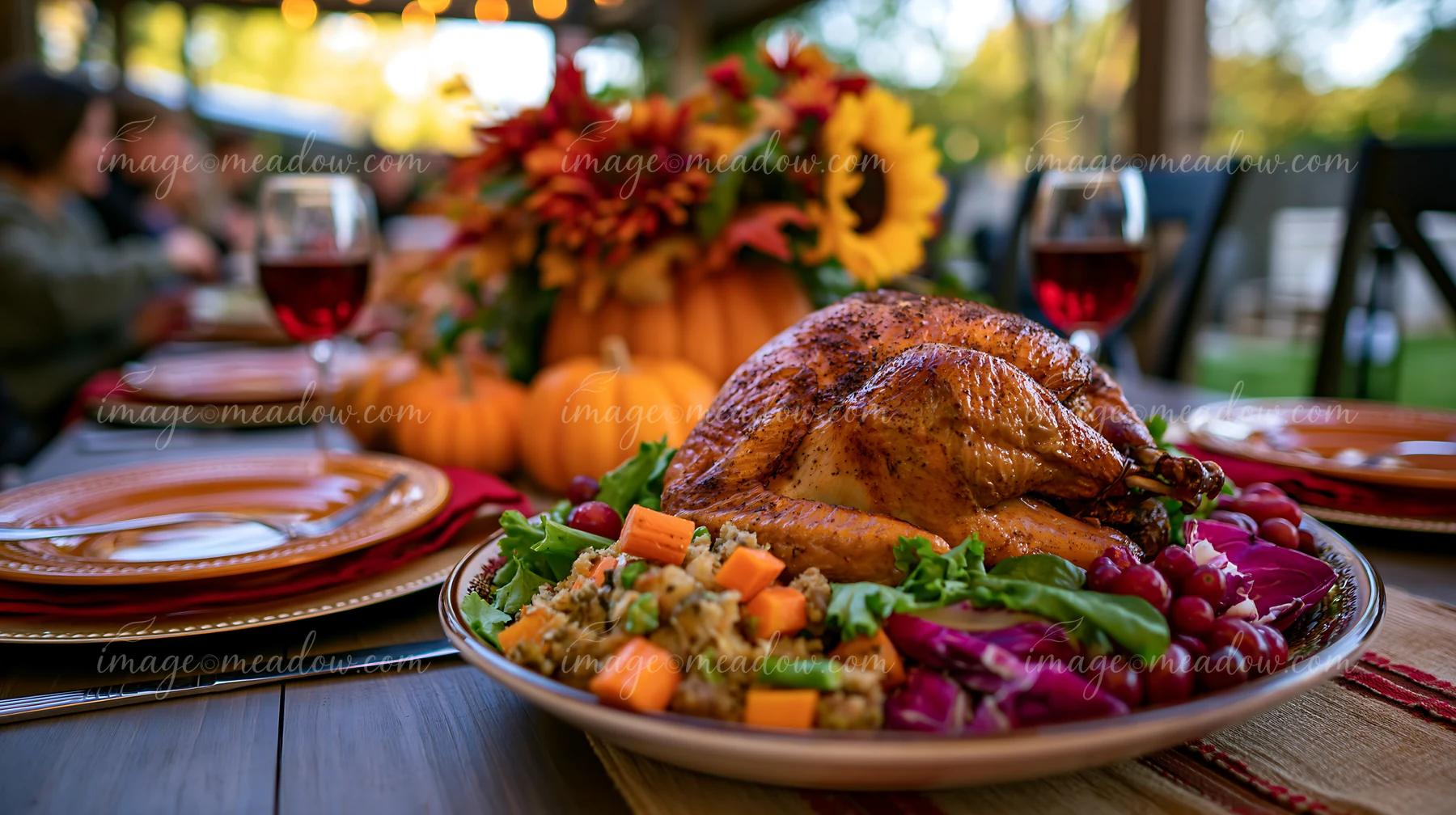 Roasted turkey surrounded by salad, stuffing, pumpkins, flowers, plates, and wine glasses on a festive dining table.