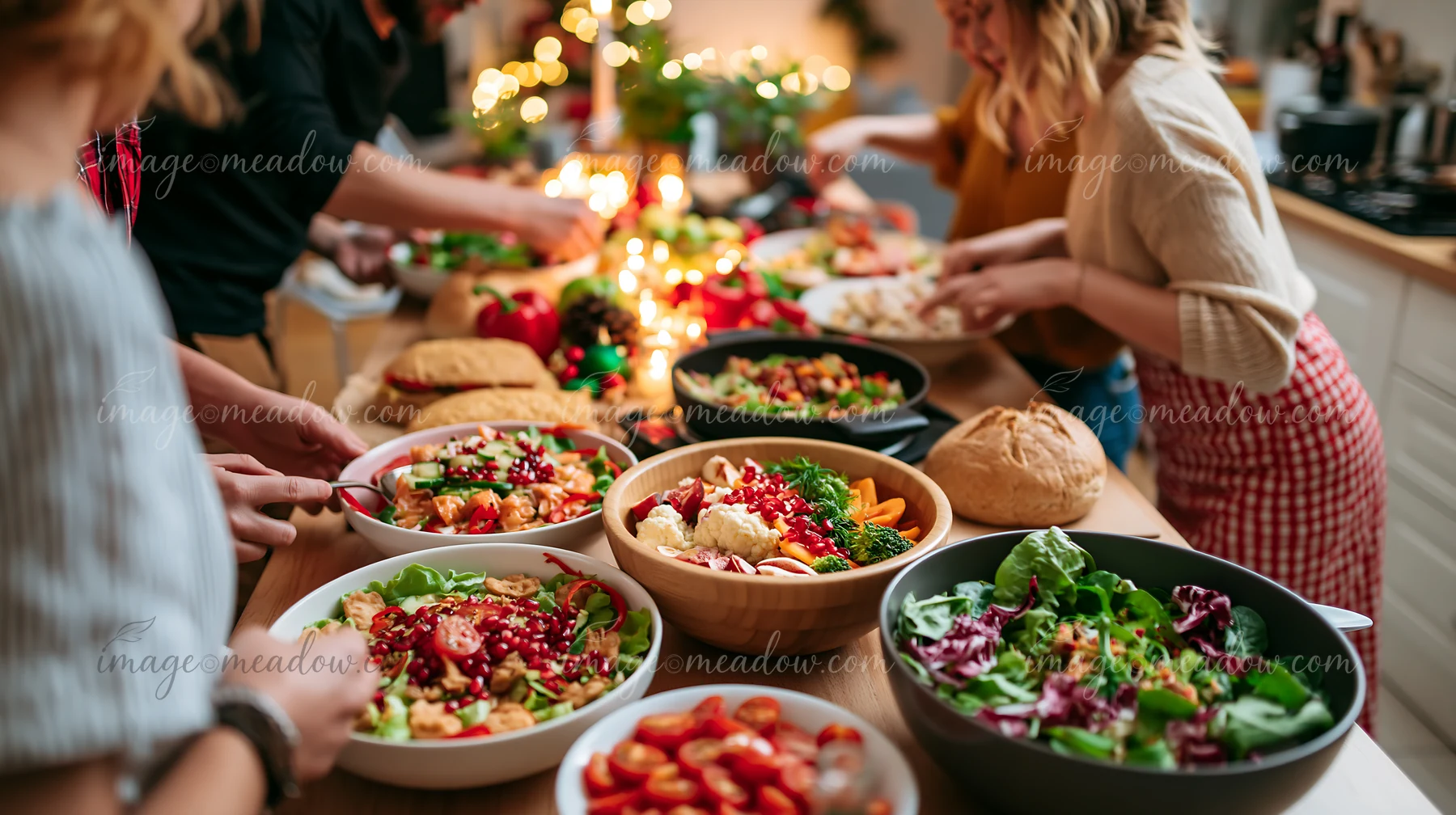 Several people prepare colorful Christmas dishes around a festive kitchen table with warm lights.
