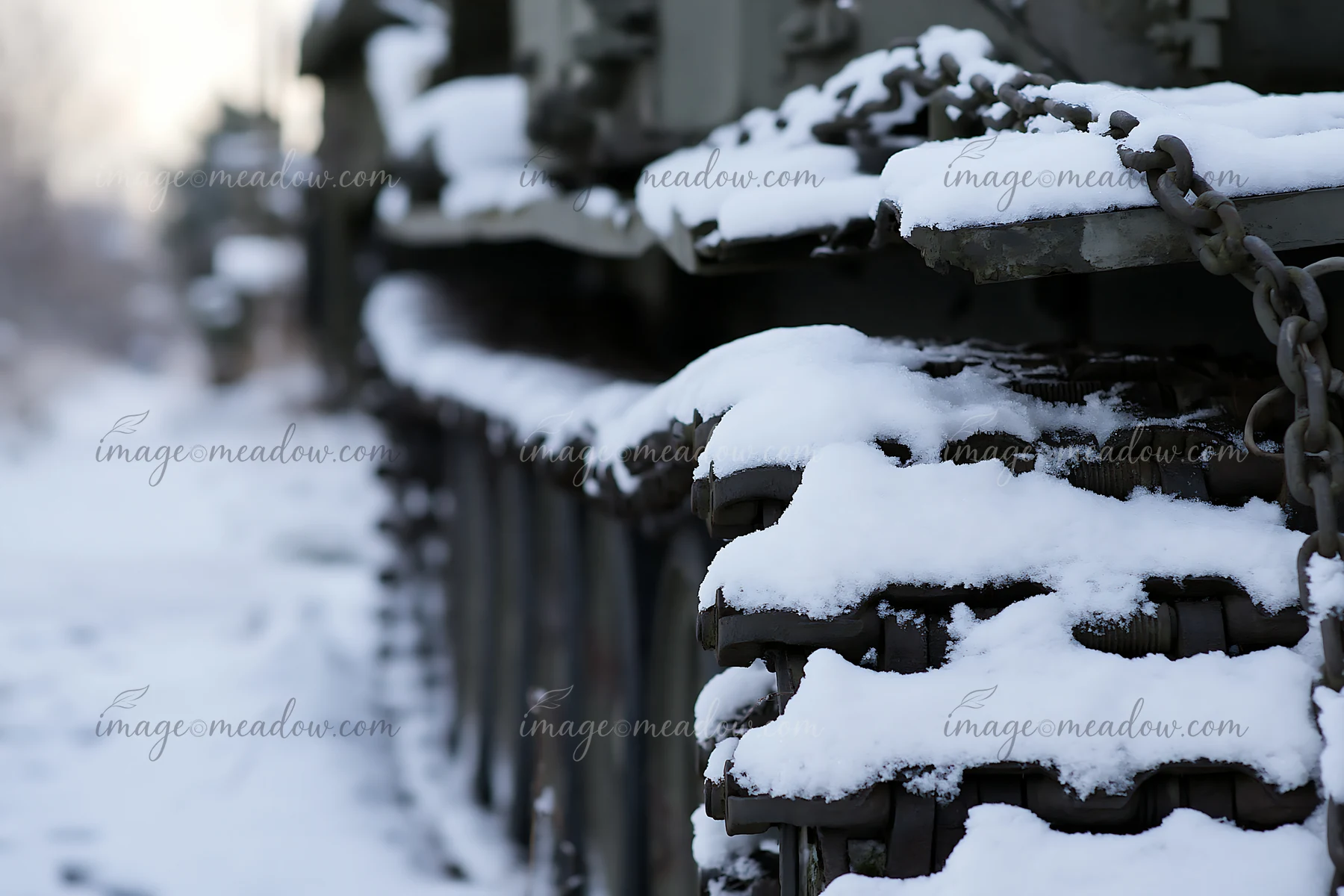 Snow covers the tracks of a panzer tank, highlighting the rugged texture and design.