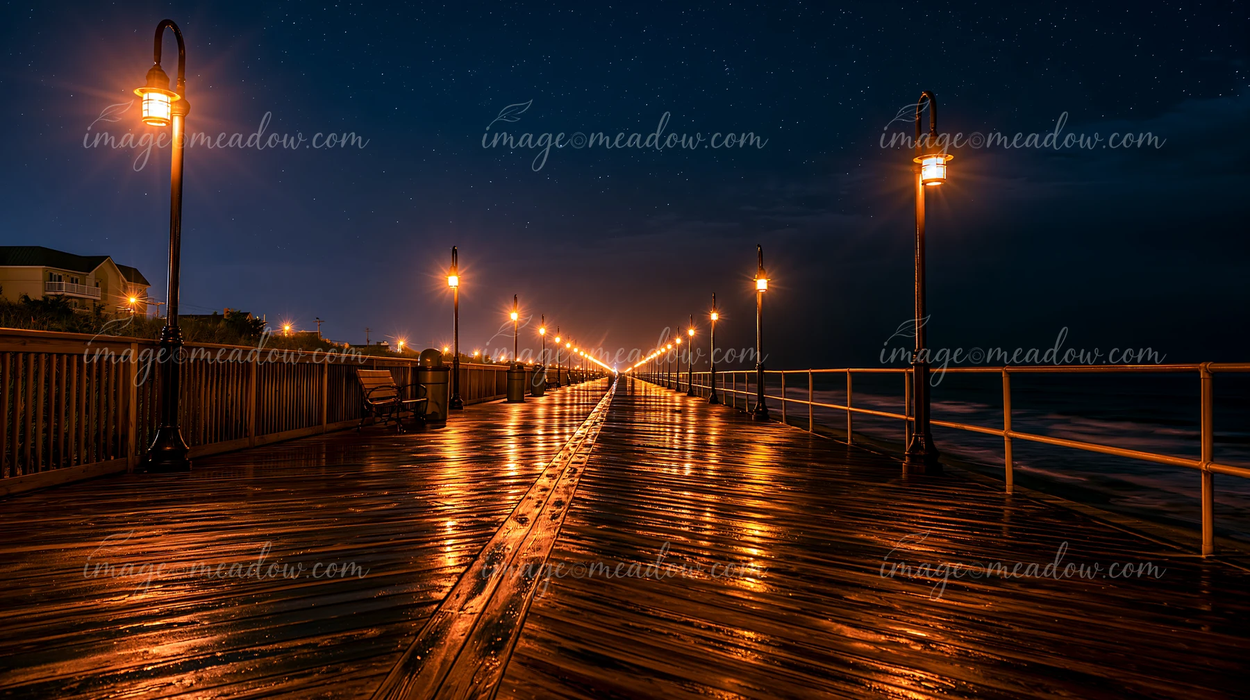 Stars fill the sky above a wooden boardwalk lined with lights.