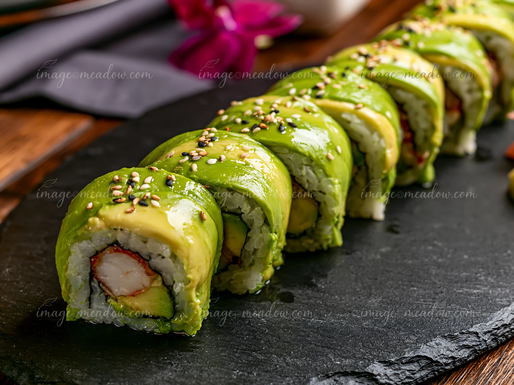 The dragon roll close-up shows a vibrant sushi dish with avocado, crab, and cucumber placed on a black slate plate.