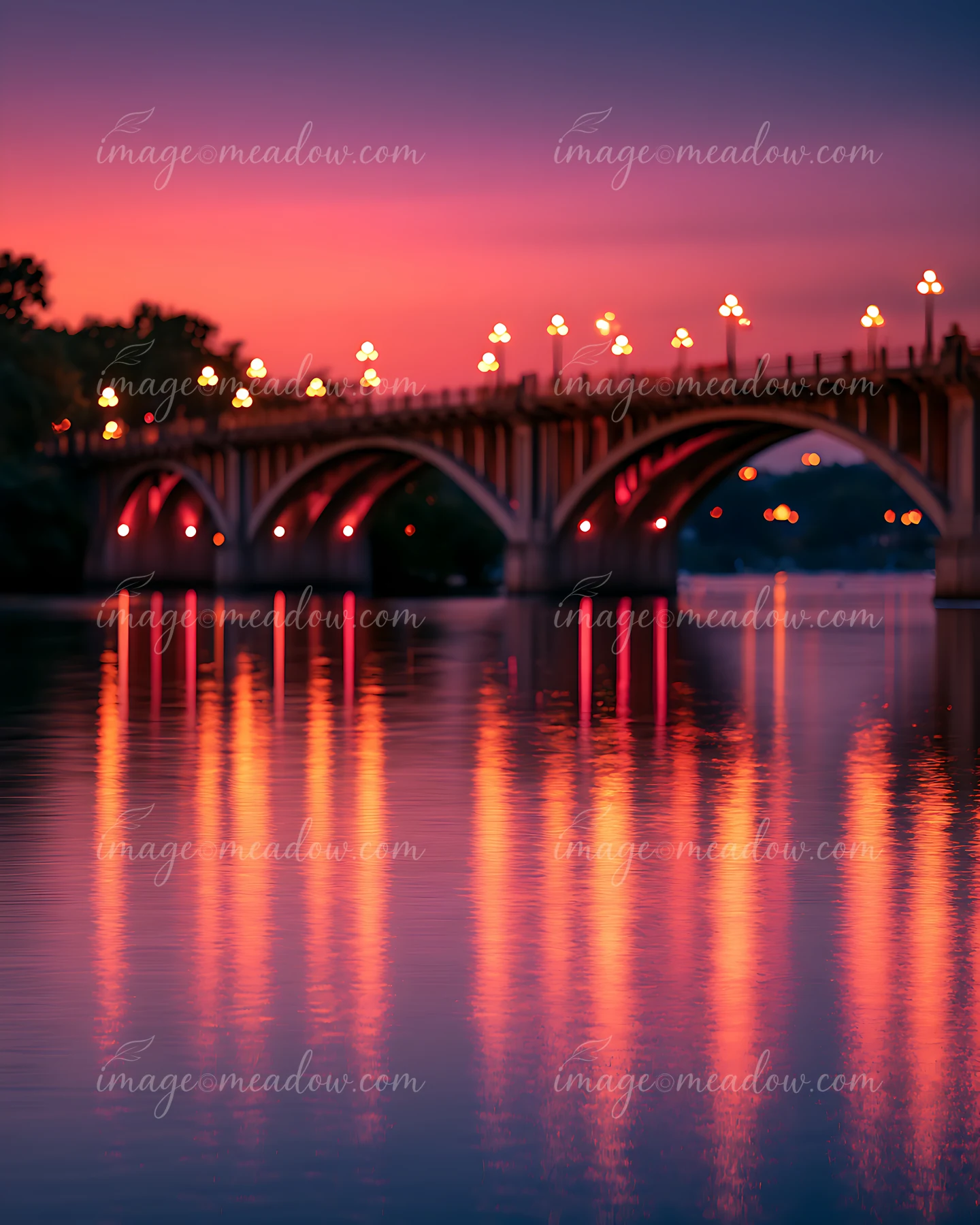 The scene shows a bridge with lights reflecting on calm water at sunset.