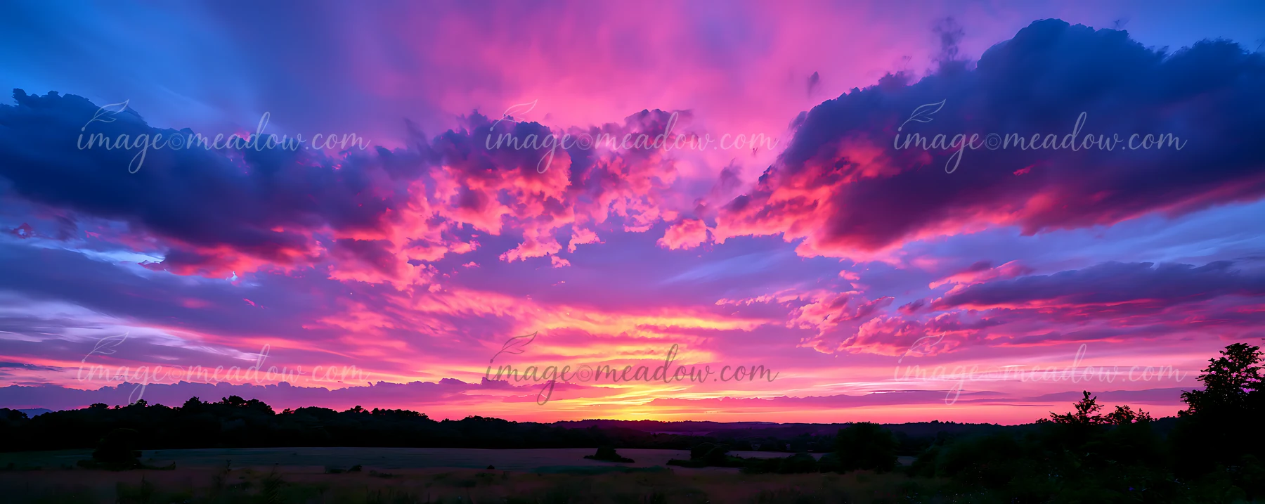 The sky displays a mix of pink, purple, and blue hues as the sun sets over a rural field.