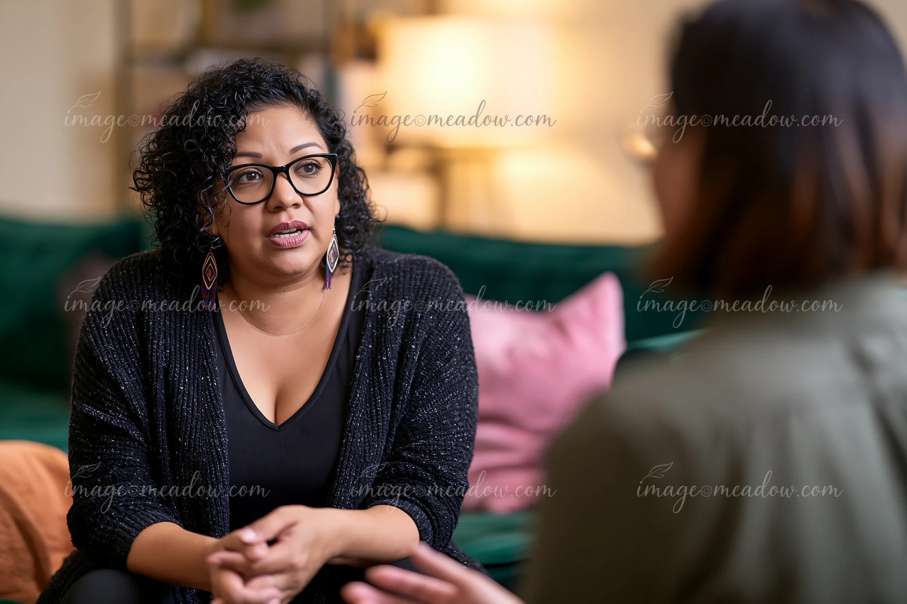 Therapist listens attentively to a bereaved person during a counseling conversation in a comfortable living room.