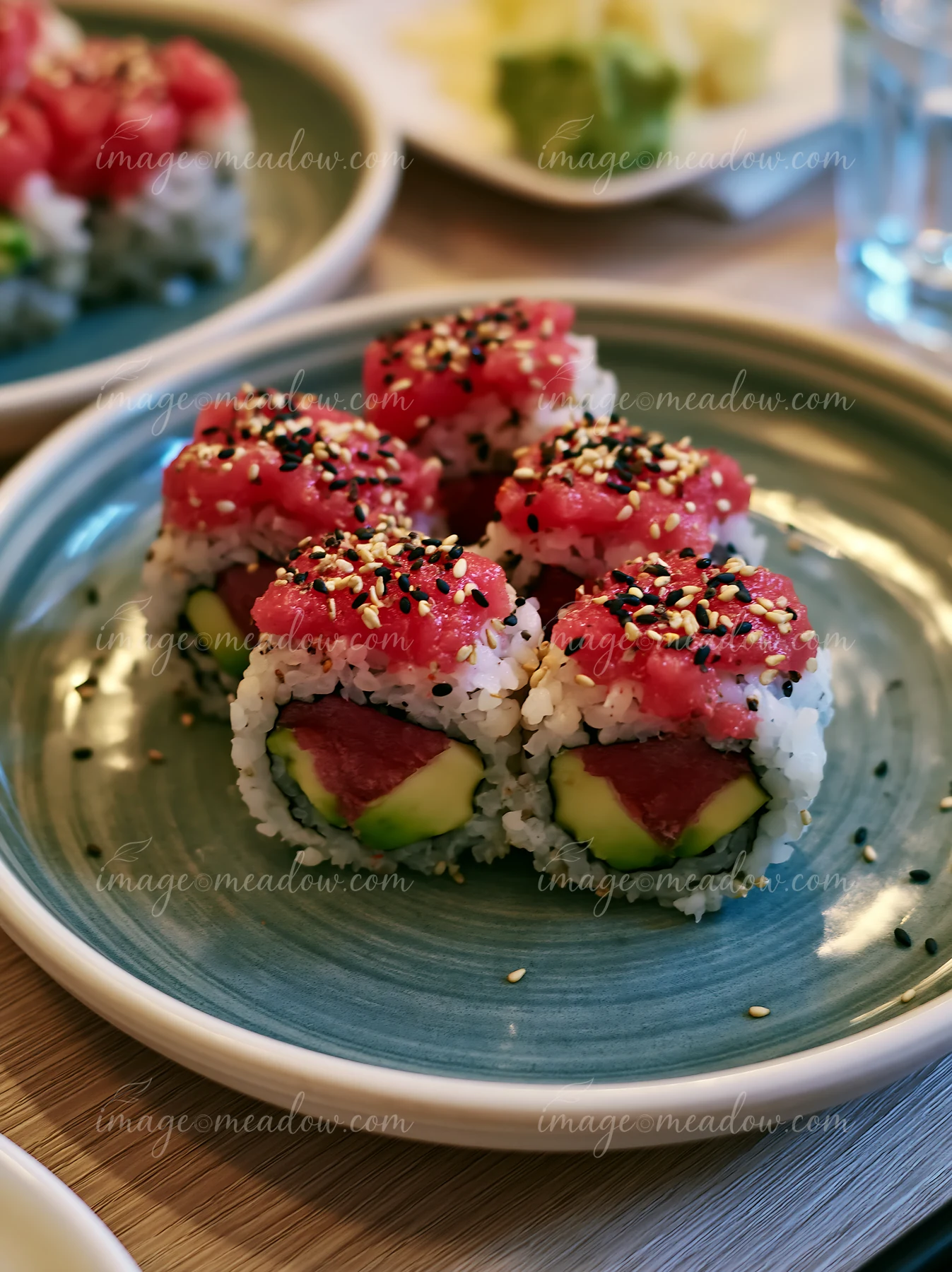 This close-up shows a plate of sushi with spicy tuna rolls topped with sesame seeds.