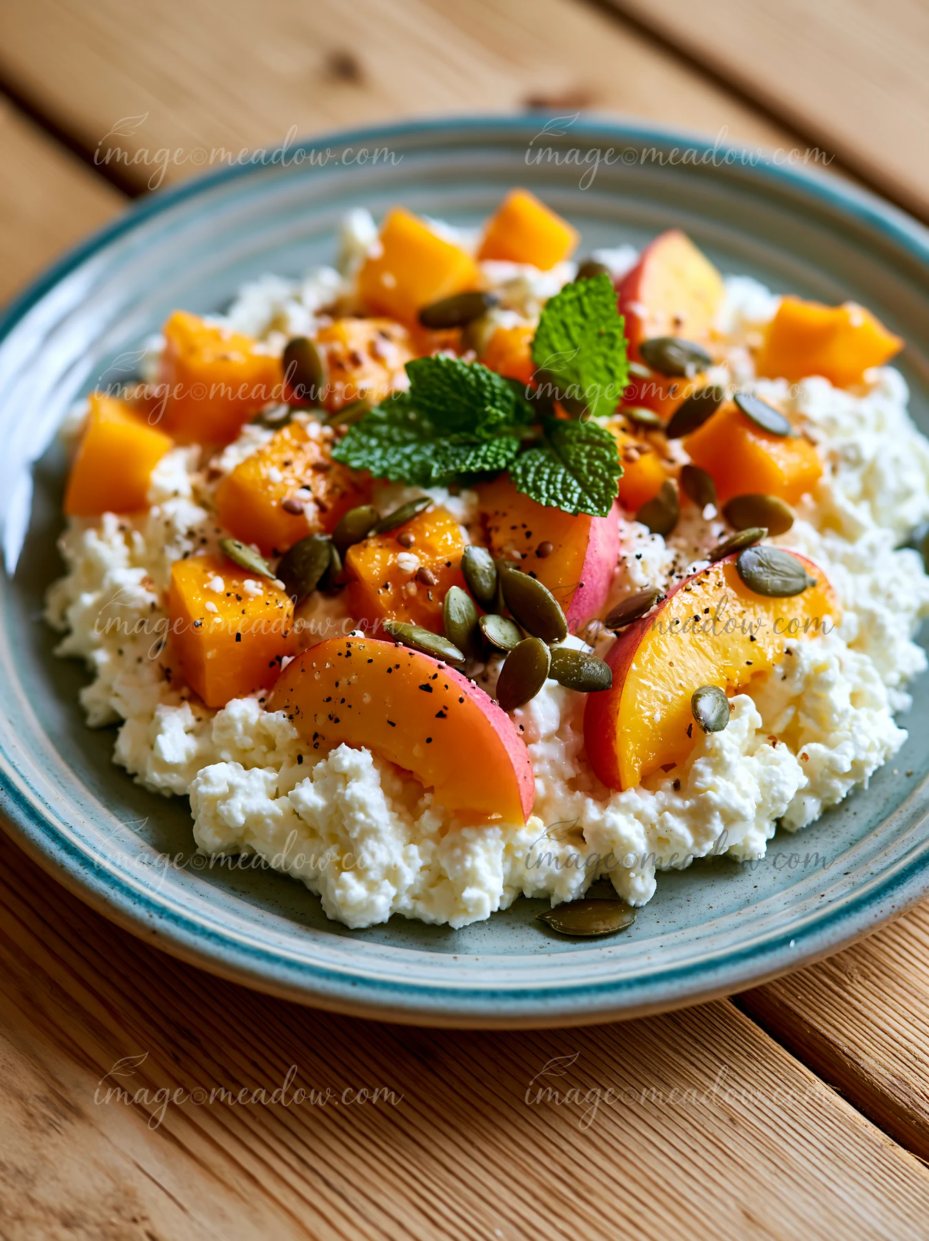 This plate features cottage cheese topped with peach and pumpkin seeds on a wooden table.