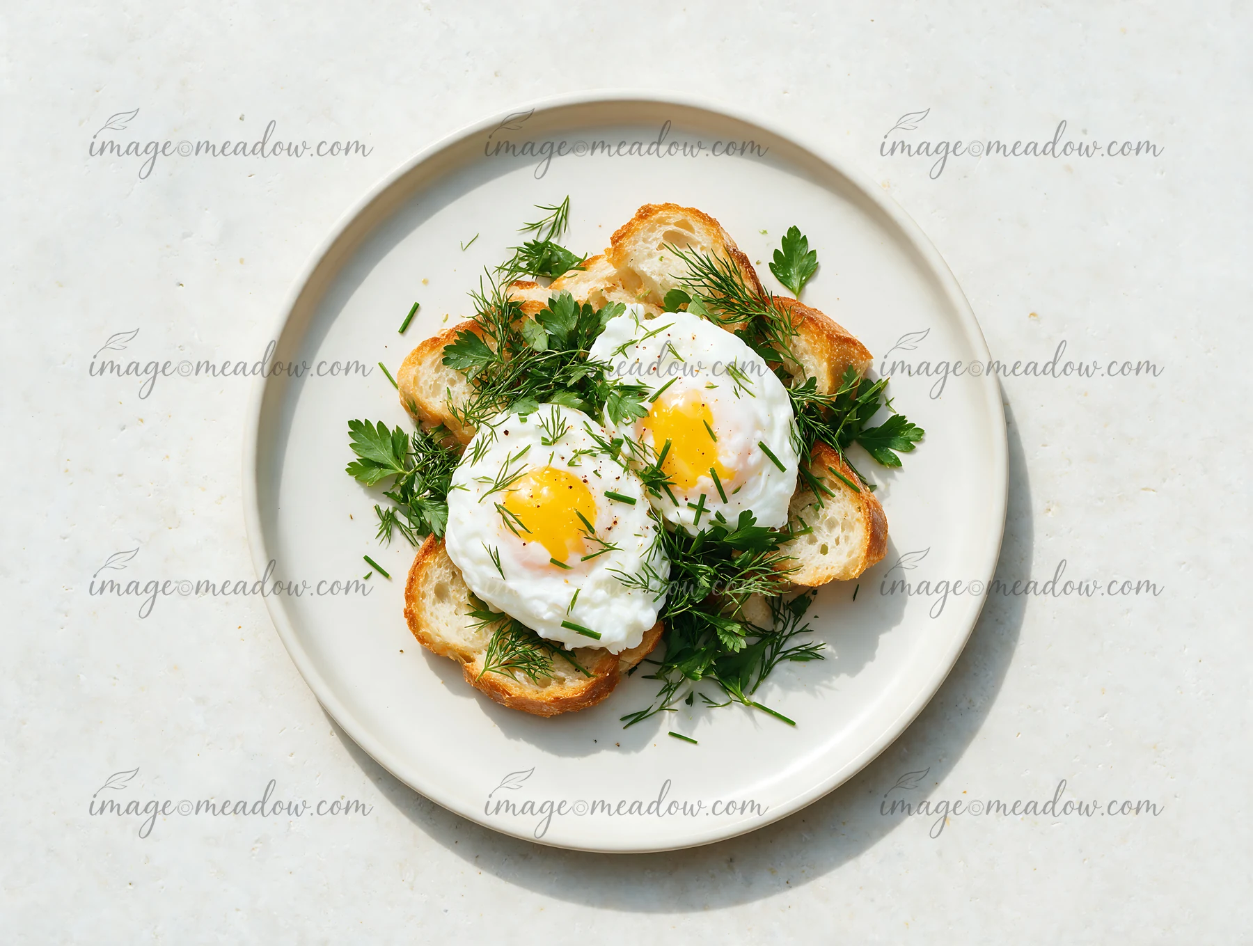 Top view of two poached eggs with herbs and toasted bread on a white breakfast plate.