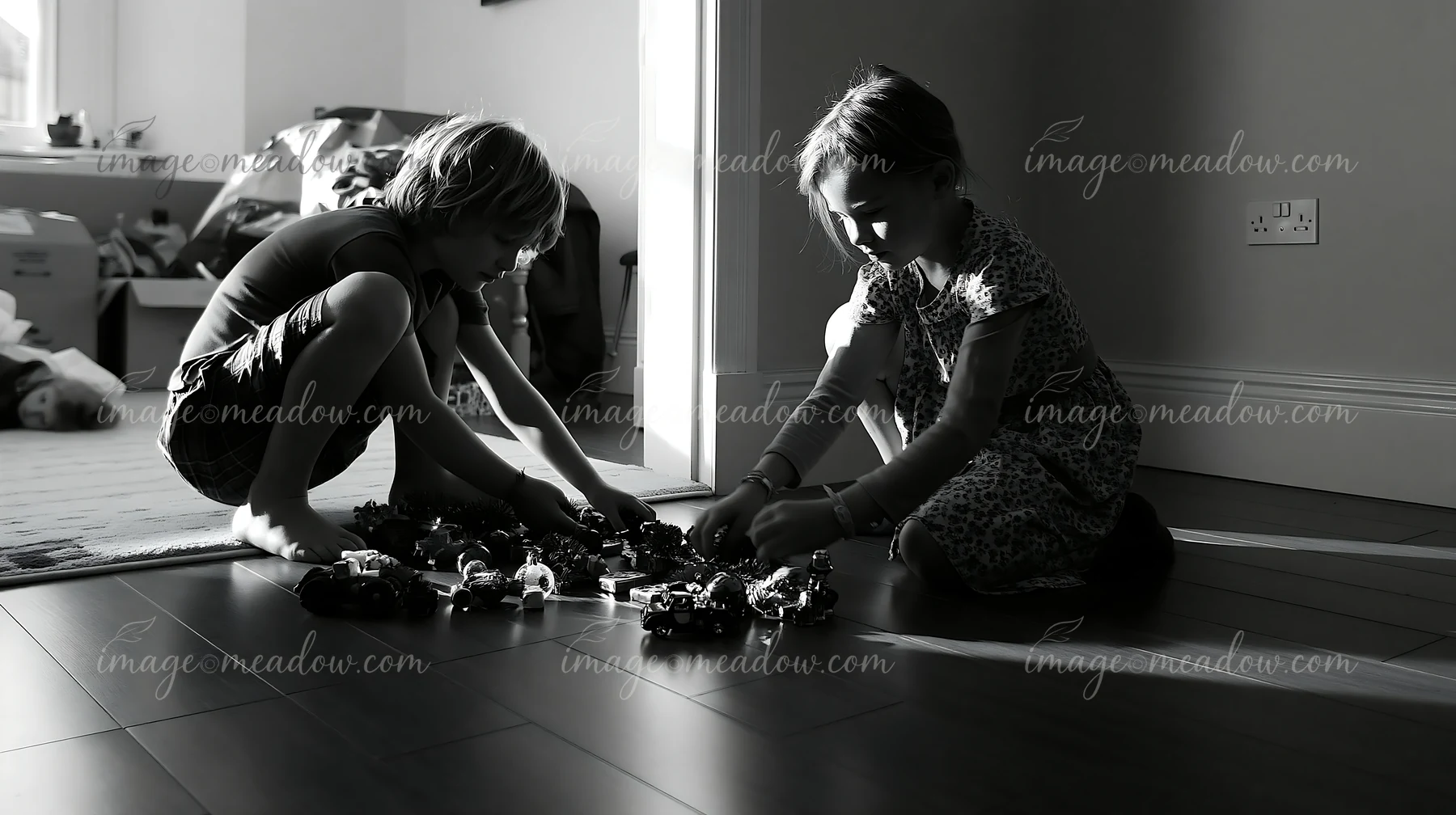 Two children sort Christmas ornaments and tinsel on a tiled floor in a sunlit home.