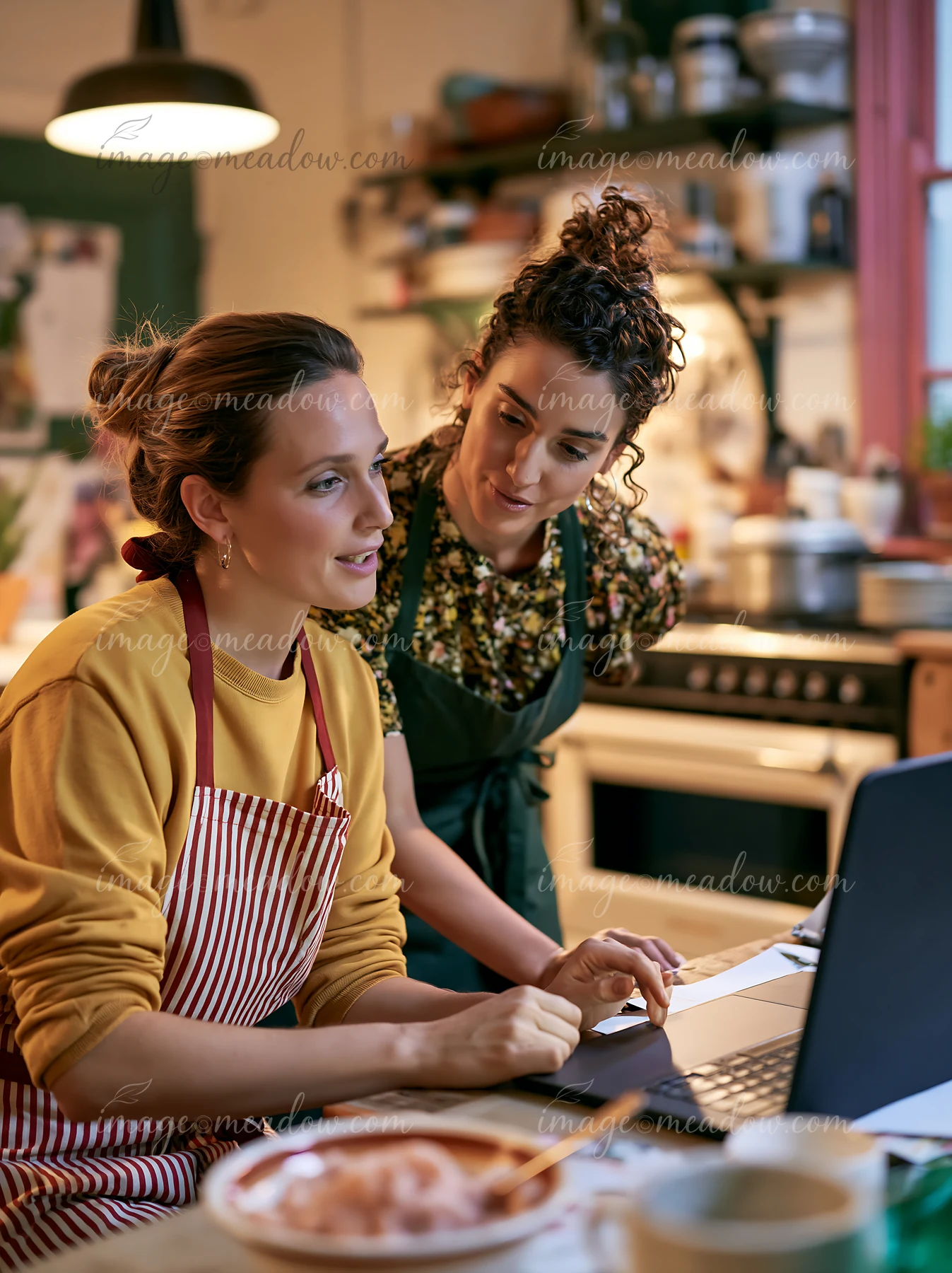 Two women are engaged in a conversation at a kitchen table.