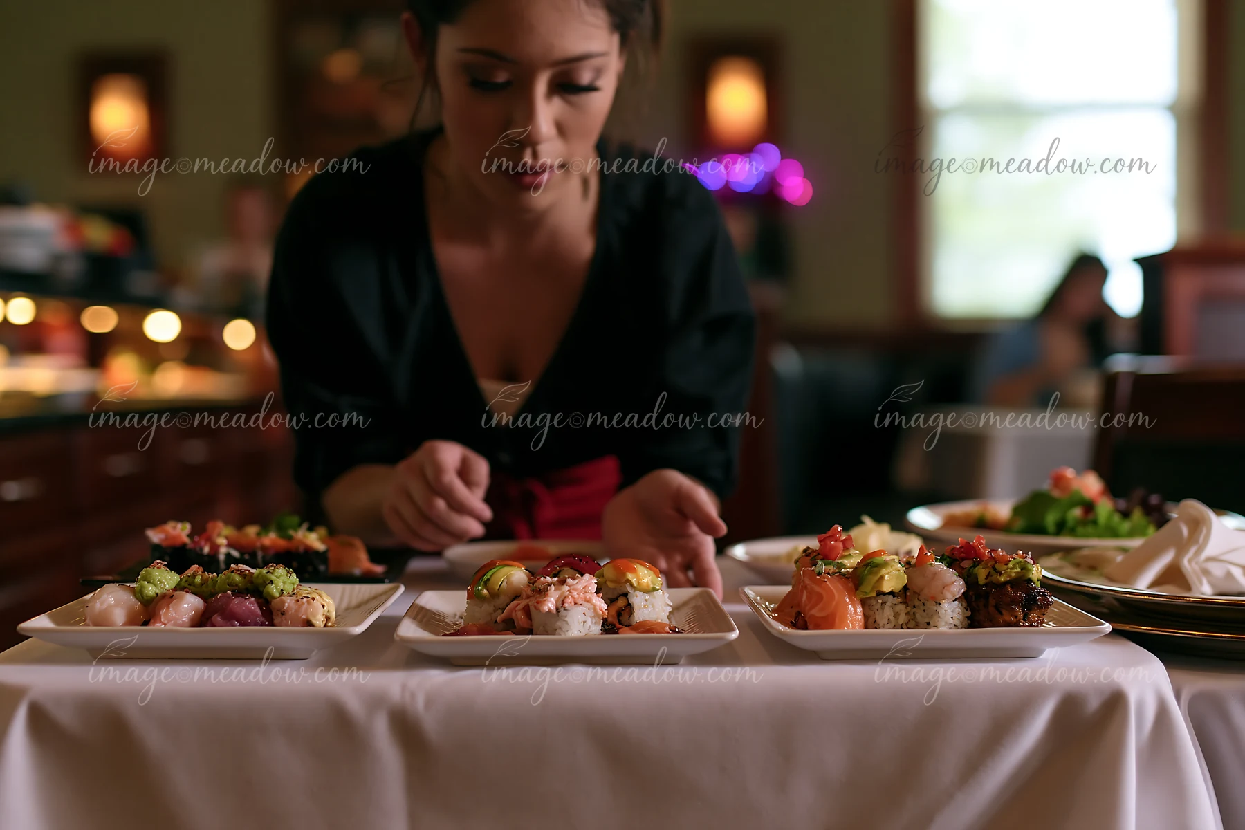 Waitress arranges sushi plates at a restaurant, showcasing various sushi types on white dishes.