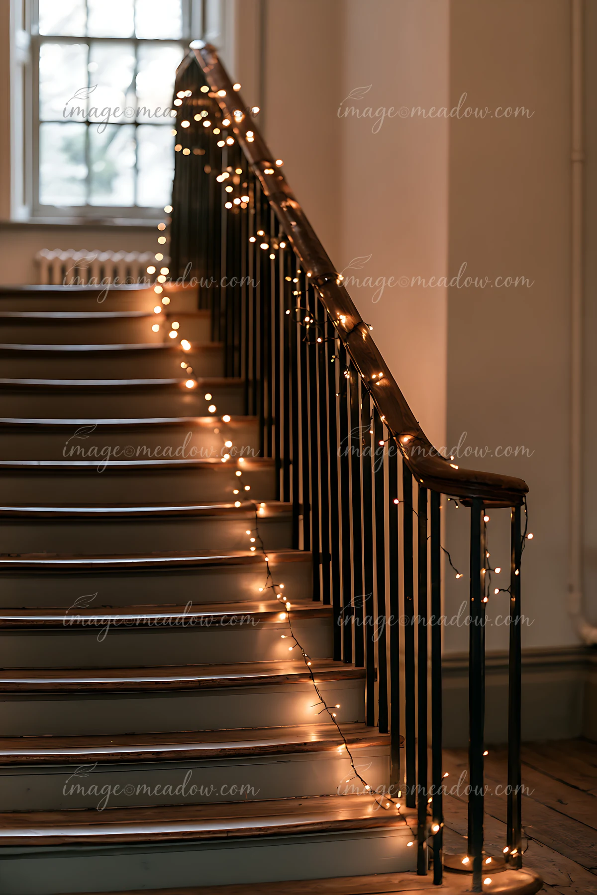 Warm string lights drape along a wooden banister and staircase in a softly lit interior.