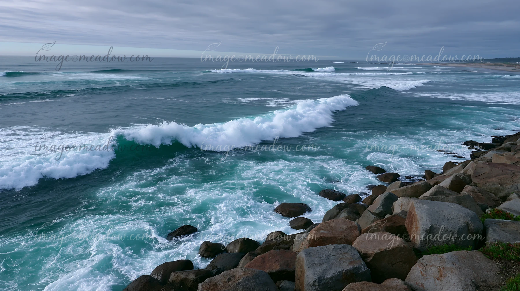 Waves crash against a rocky coastline with a protective sea wall.